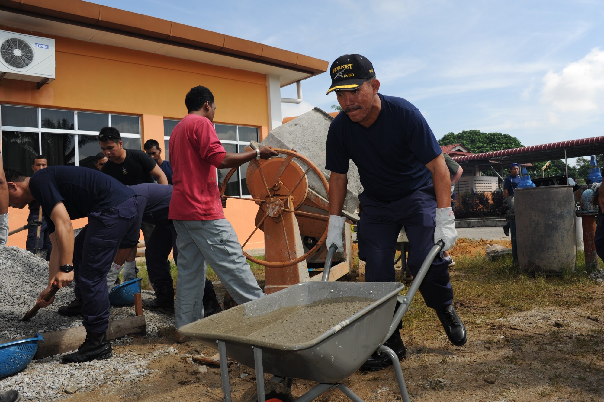 Royal Malaysian Air Force Brig. Gen. Shabre Bin HJ Hussein, TUDM Butterworth commander, pushes a load of concrete at the Pembangunan Anak-Anak Yatim Bekas Perajurit Malaysian orphanage in Kulim, Malaysia, on April 8, 2012. More than 50 U.S. Air Force and RMAF members spent the day mixing and pouring concrete to create a multi-use sports court at the orphanage as part of a humanitarian construction project held during Cope Taufan 2012.  Exercise Cope Taufan 12 is a Pacific Air Forces sponsored exercise involving dissimilar basic fighter maneuver and dissimilar air combat tactics training with the U.S. and Royal Malaysian Air Forces at Tudm Butterworth, Malaysia, 4-13 Apr 12. (U.S. Air Force photo/Master Sgt. Matt Summers)