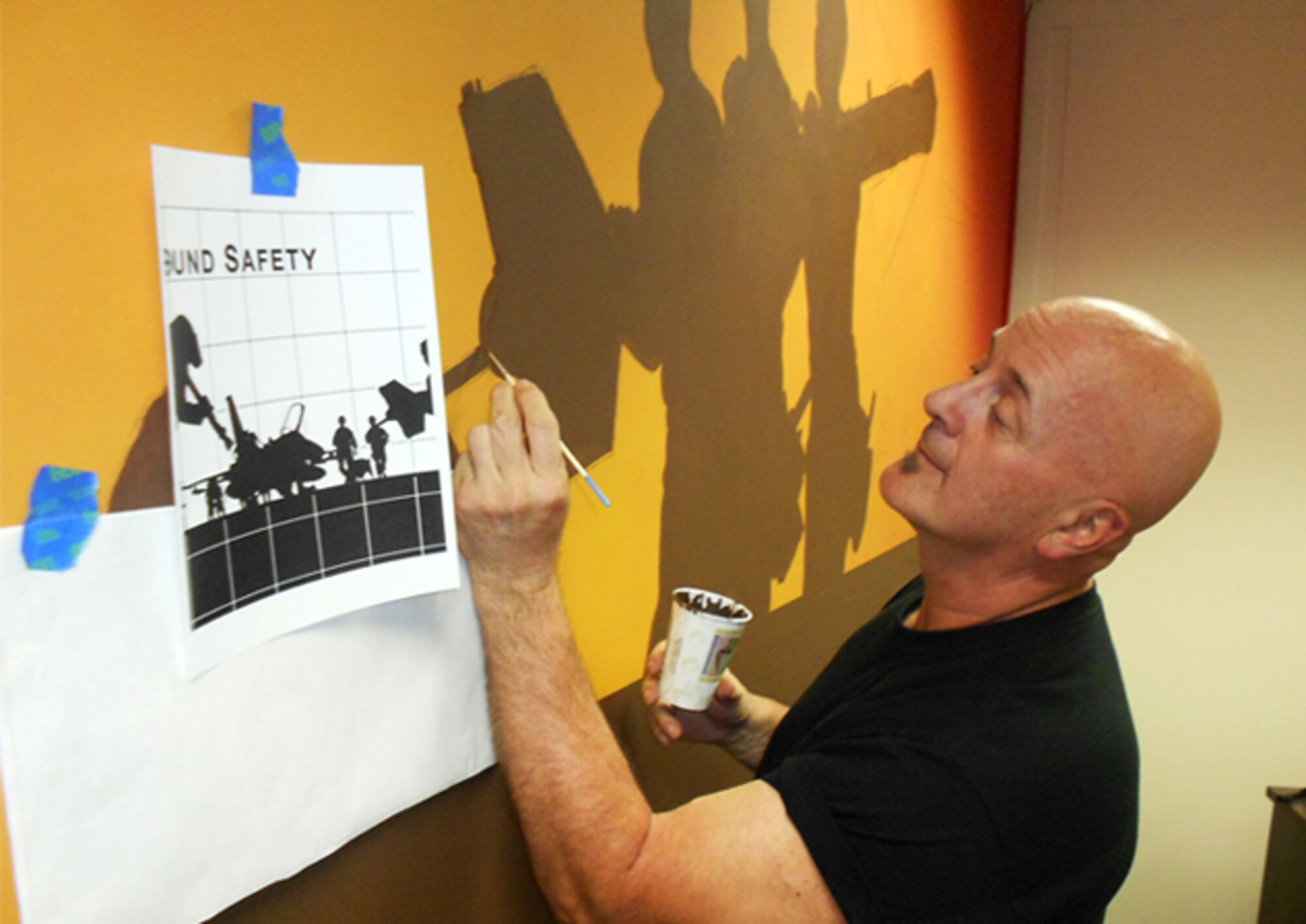 Dan Harman, Air Force Safety Center graphic artist and designer, details a silhouette to be further refined on a second coat as part of a mural to cover 153 square feet in the Ground Safety Division conference room. Harman, who will retire April 30 with 23 years of federal service, was asked to create the mural as a visual reminder that ground safety impacts everyone, on and off duty. (U.S. Air Force photo by Lt. Col. Cindi Feldwisch)