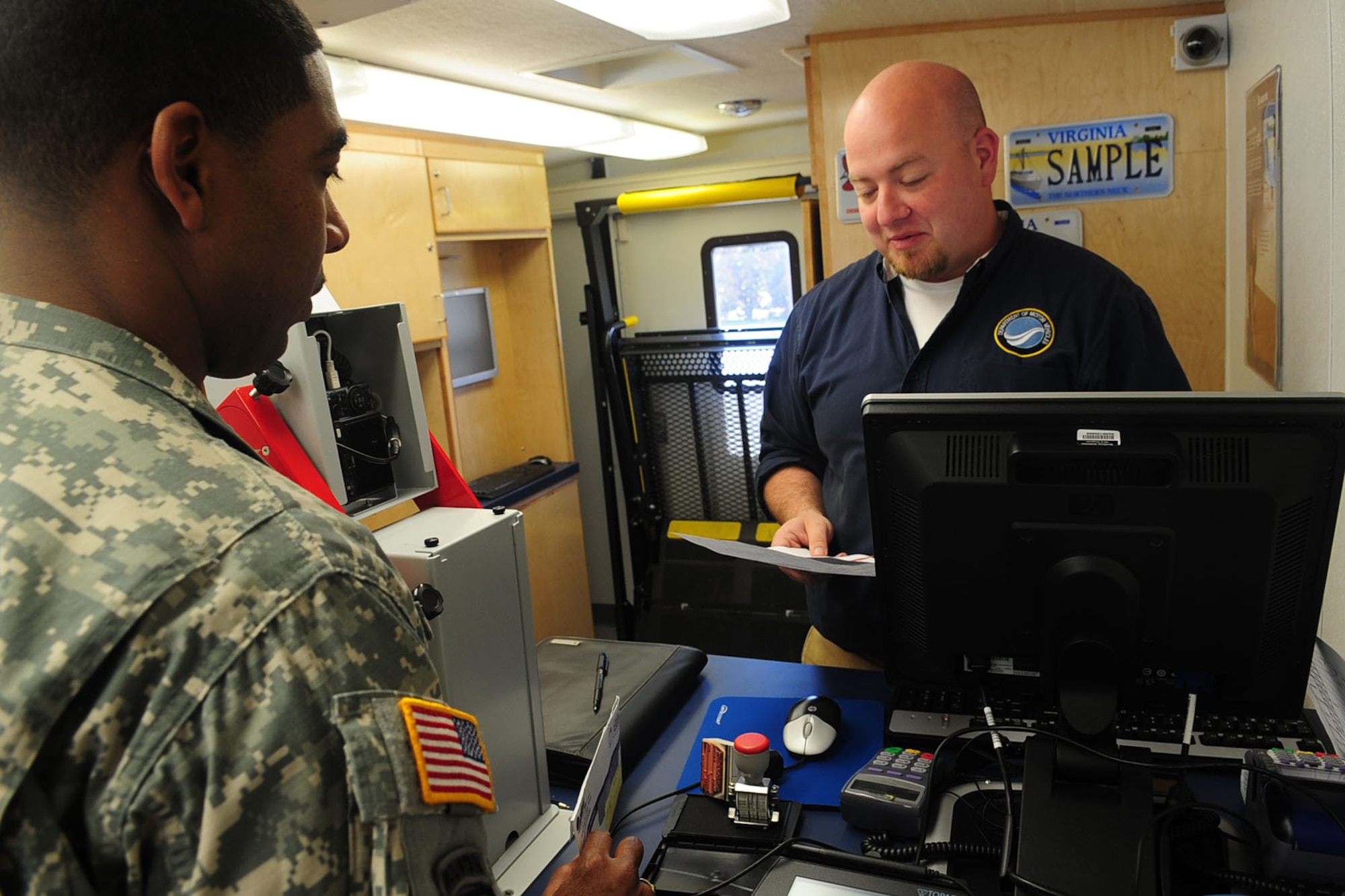 Jonathan Butner, assistant manager of the  Department of Motor Vehicles Richmond mobile unit, assists U.S. Army Sgt. Hilton Hunter, a Soldier assigned to Fort Eustis' Warrior Transition Unit, in renewing his motorcycle registration inside the DMV 2 Go at Fort Eustis, Va., April 10, 2012. The office-on-wheels is equipped to process all DMV transactions, such as applying for or renewing your driver's license and ordering disabled parking placards or plates. (U.S. Air Force photo by Staff Sgt. Ashley Hawkins/Released)
