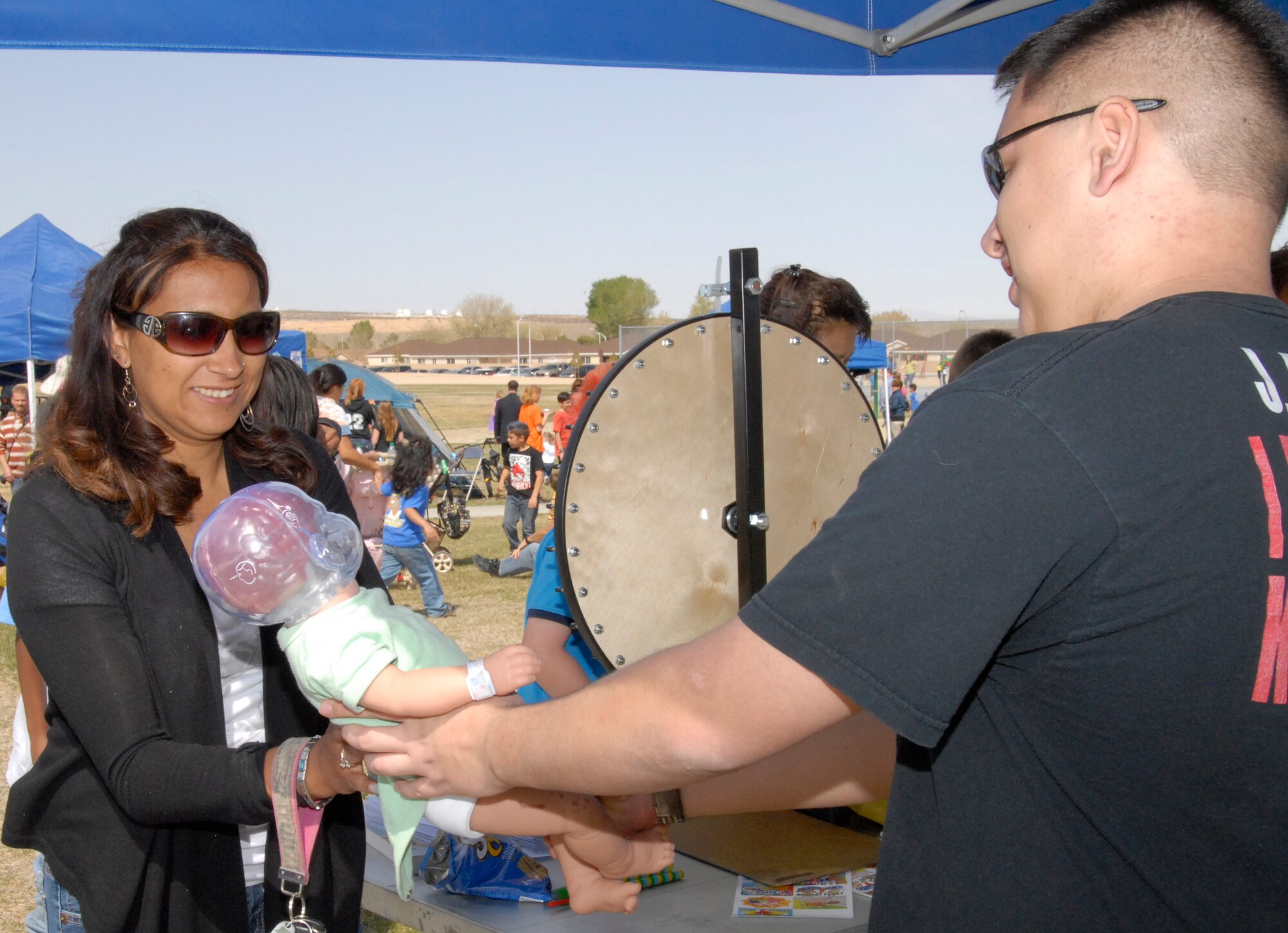 Angela Baylee, Air Force spouse, receives a Shaken Baby Syndrome demonstration while attending Play Day in the Park. After shaking the demonstration doll, red lights flash, indicating where brain damage has occurred. The demonstration played a key role in the Play Day in the Park event, which aimed to raise awareness about child abuse prevention. (Air Force Photo by Laura Mowry)