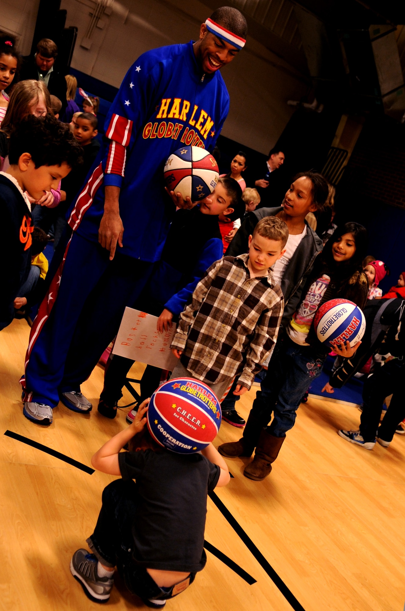 Harlem Globetrotter Hammer Harrison watches as a child performs a basketball trick at the Youth Center on Grand Forks Air Force Base, N.D., on April 9, 2012. He came to GFAFB to motivate and educate children with the program “C.H.E.E.R. For Character” designed by the Globetrotters. This program helps children become better prepared for challenges they will face as young adults. (U.S. Air Force photo by Staff Sgt. Amanda Grabiec)
