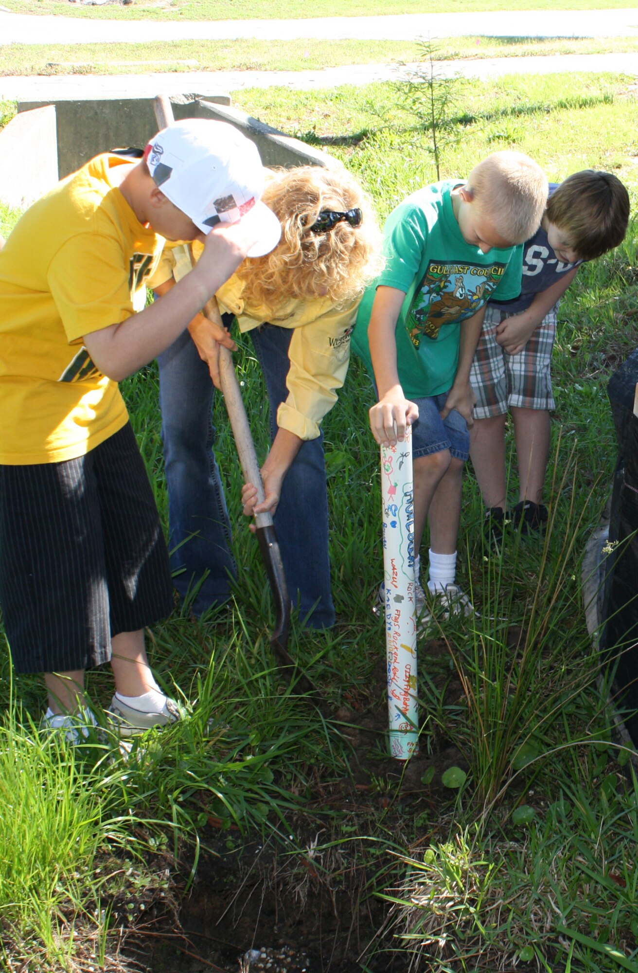 Kristal Walsh, natural/cultural resources manager of 1st Special Operations Civil Engineer Squadron, shovels as Hurlburt Field Youth Center children place a PVC pipe frog house near a creek outside the base child development center at Hurlburt Field, Fla., April 6, 2012. The Cuban tree frog, an invasive species, are attracted to these types of houses, which will be used to monitor the frog's population. (Courtesy photo)