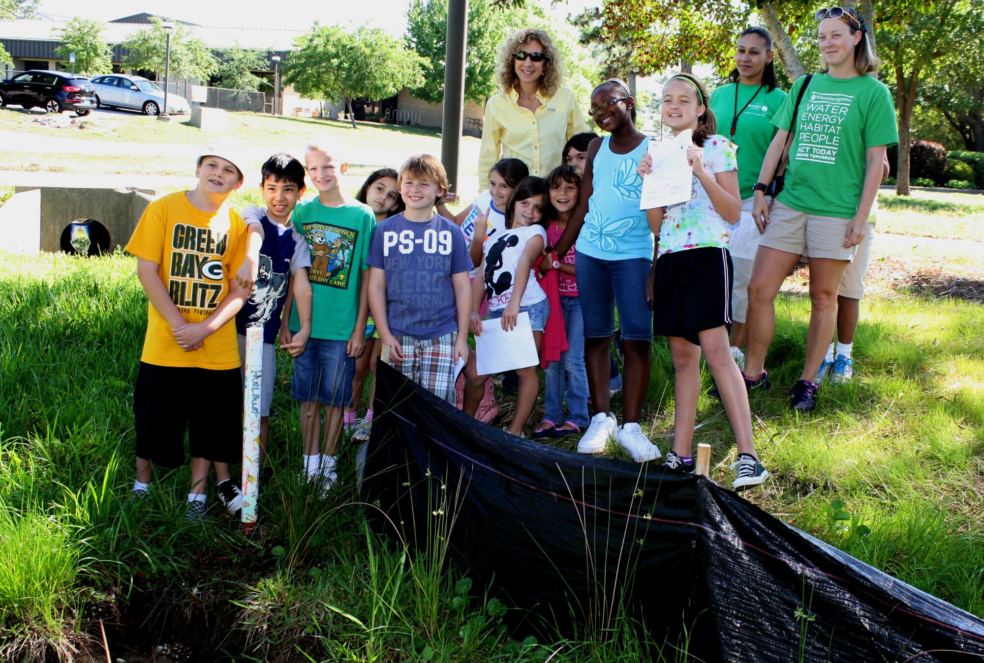 Hurlburt Field Youth Center children and staff pose with Kristal Walsh, natural/cultural resources manager of 1st Special Operations Civil Engineer Squadron, center, after placing a PVC pipe frog house near a creek outside the base child development center at Hurlburt Field, Fla., April 6, 2012.  The house will be used to monitor the population and movement of the Cuban tree frog, an invasive species. (Courtesy photo)