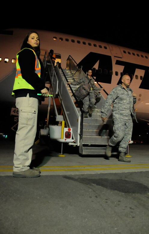 Hali Snuffin, CAV International employee, escorts U.S. Air Force Airmen off of a Boeing 747-400 freighter aircraft at an undisclosed location in Southwest Asia, March 11, 2012.  Snuffin and other CAV International employees handle airfield services and logistics for the 5th Expeditionary Air Mobility Squadron. (U.S. Air Force photo by Staff Sgt. James Lieth/Released)