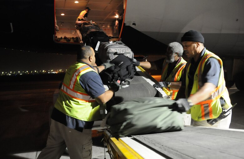 (From left), Brandon Tucker, Randy Bryant, and Benton Peeples, CAV International employees, unload baggage off of a Boeing 747-400 freighter aircraft at an undisclosed location in Southwest Asia, March 11, 2012. CAV International employees handle airfield services and logistics for the 5th Expeditionary Air Mobility Squadron and the U.S. Air Force's Air Mobility Command around the world. (U.S. Air Force photo by Staff Sgt. James Lieth/Released)