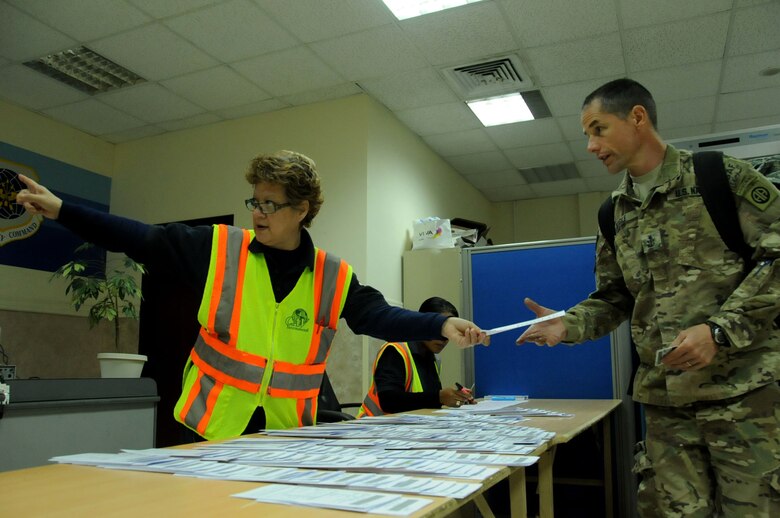 Linda Curetl, CAV International employee, hands out travel tickets to departing military members at an undisclosed location in Southwest Asia, March 11, 2012.  CAV International employees handle airfield services and logistics for the 5th Expeditionary Air Mobility Squadron and the U.S. Air Forces Air Mobility Command around the world. (U.S. Air Force photo by Staff Sgt. James Lieth/Released)