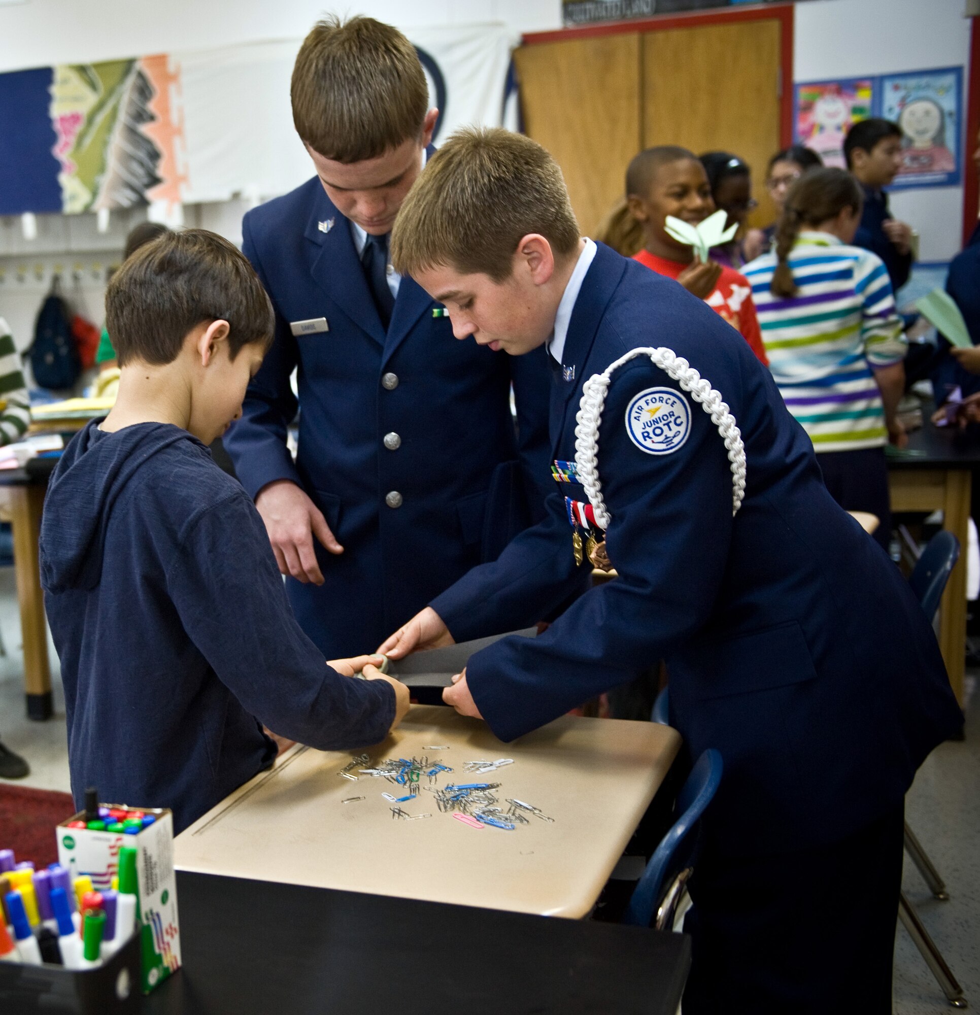 YOKOTA AIR BASE, Japan -- Johnathan Crumpton (middle), and Joshua Davids (right), both Junior Reserve Officers' Training Corps students, assist Kai Morgan, a 5th grade student at Joan K. Mendel Elementary School, with making a paper airplane as a part of Science, Technology, Engineering and Math Week at Yokota Air Base, Japan, Apr. 4, 2012. Students participated in various activities involving science, engineering and math. (U.S. Air Force photo/Airman 1st Class Krystal M. Garrett) 