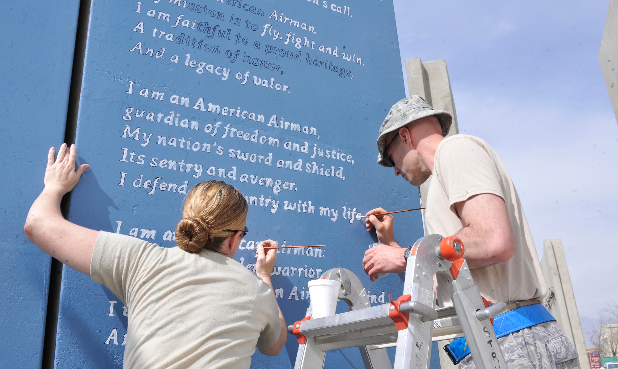 Master Sgt. Kathryn Manning, 455 Air Expeditionary Wing Superintendent of Chapel Operations and Master Sgt. Joshua Franklin, 455 AEW Superintendent of Ground Safety and Wing Staff Agencies, display Air Force pride as they apply the finishing touches on the
Airman's Creed Wall at Camp Cunningham at Bagram.  They are members of Bagram's Top 3 organization who sponsored the painting of the giant-sized image at the camp's outer edges. The Airman's Creed Wall project was completed on March 27, 2012. (U.S. Air Force Photo /Airman 1st Class Ericka Engblom)
