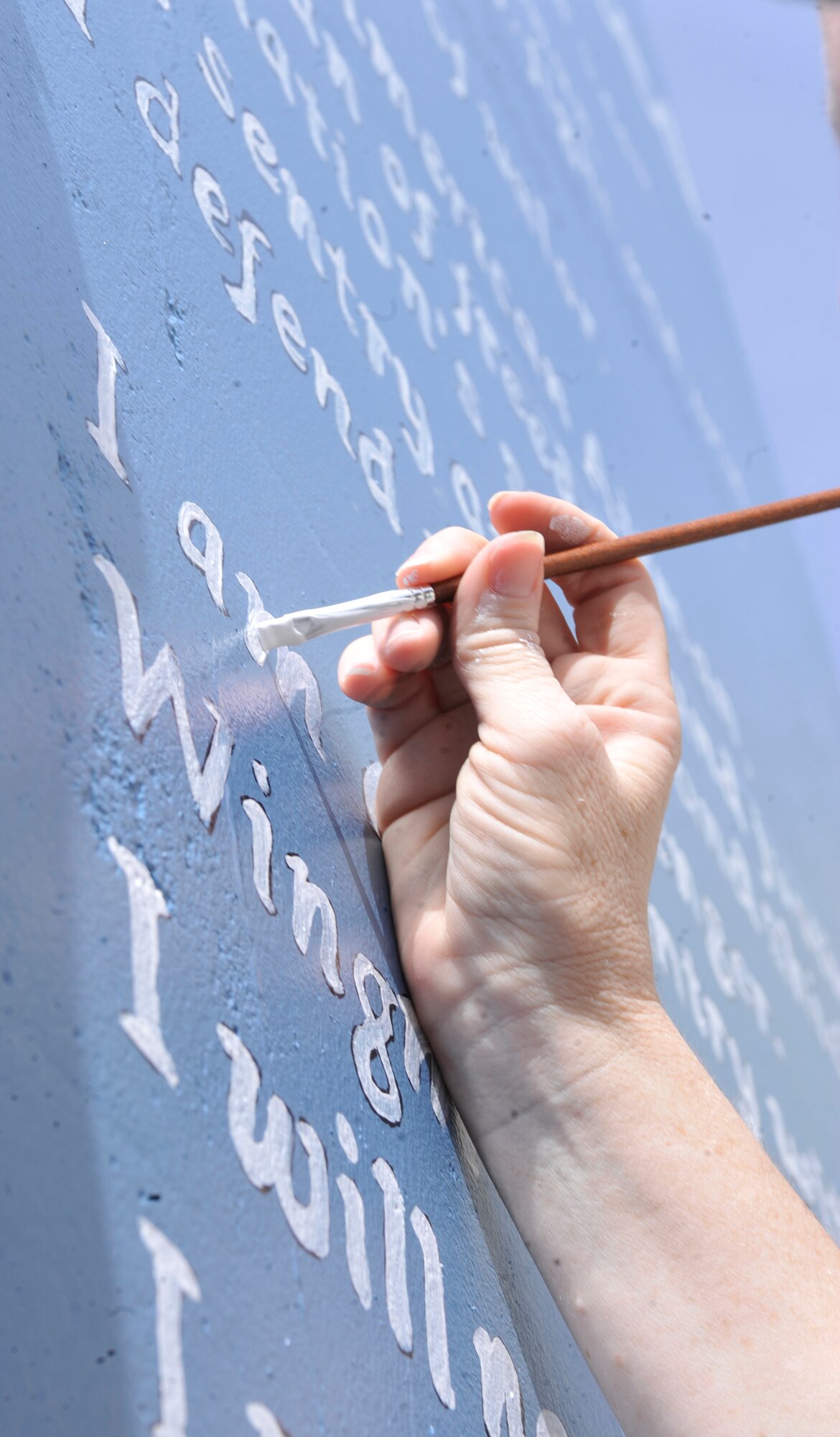 Master Sgt. Kathryn Manning, 455 Air Expeditionary Wing Superintendent of Chapel Operations, shows some Air Force pride as she applies the finishing touches on the Airman's Creed Wall at Camp Cunningham at Bagram.  She's a member of Bagram's Top 3 organization who sponsored the painting of the giant-sized image at the camp's outer edges. The Airman's Creed Wall project was completed on March 27, 2012. (U.S. Air Force Photo /Airman 1st Class Ericka Engblom)