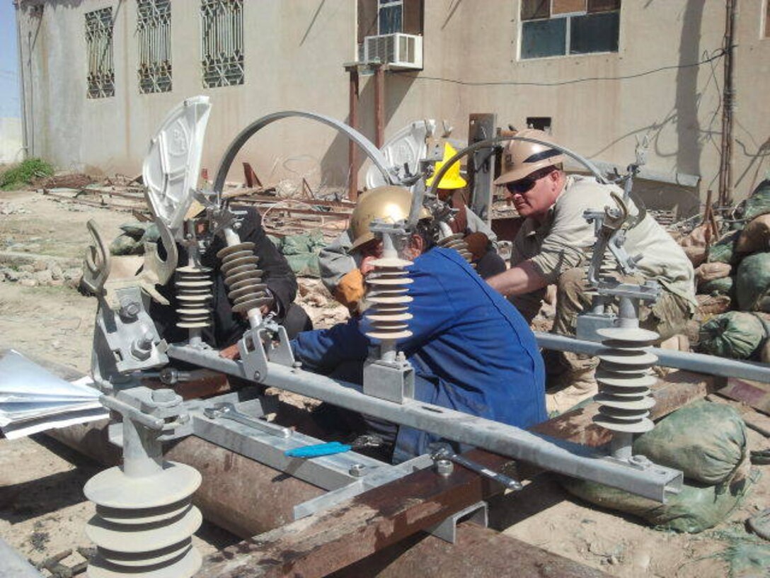 AFGHANISTAN -- Staff Sgt. Scott Michael and an Afghan utility technician assemble the air disconnect switch as part of the Sangin substation upgrade project in early March, in southern Afghanistan.           