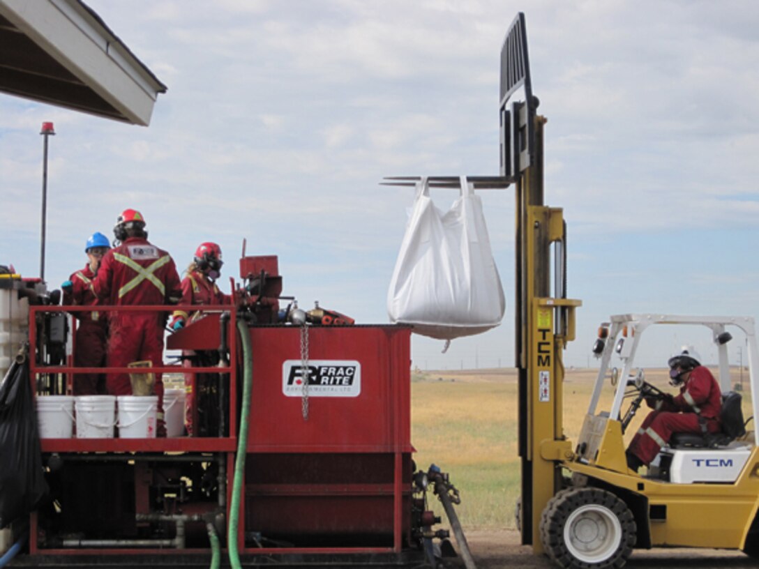 Contractor's field crew lifts a super-sack containing micro-scale zero-valent iron/organic carbon into position above the mixing tank so that the material can be blended into the amendment formulation that will be injected into groundwater via hydraulic fracturing.                   