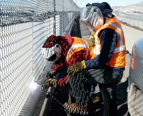 Workers fix a breach in the border fence along the U.S.-Mexico Border.  
