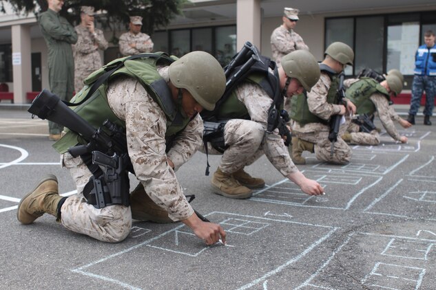 Provost Marshal’s Office Special Reaction Team candidates plan out different ways they would be able to enter a room from various angles during an SRT indoctrination brief at an empty lot behind Matthew C. Perry Schools here April 10, 2012. The candidates started their indoctrination brief at 4:30 a.m., running a Physical Fitness Test. Once the candidates finished the day long training indoc, they took an oral examination followed by a written test. For consideration into SRT, the Marines must have a first class PFT and Combat Fitness Test and must be at a minimum rank of lance corporal.