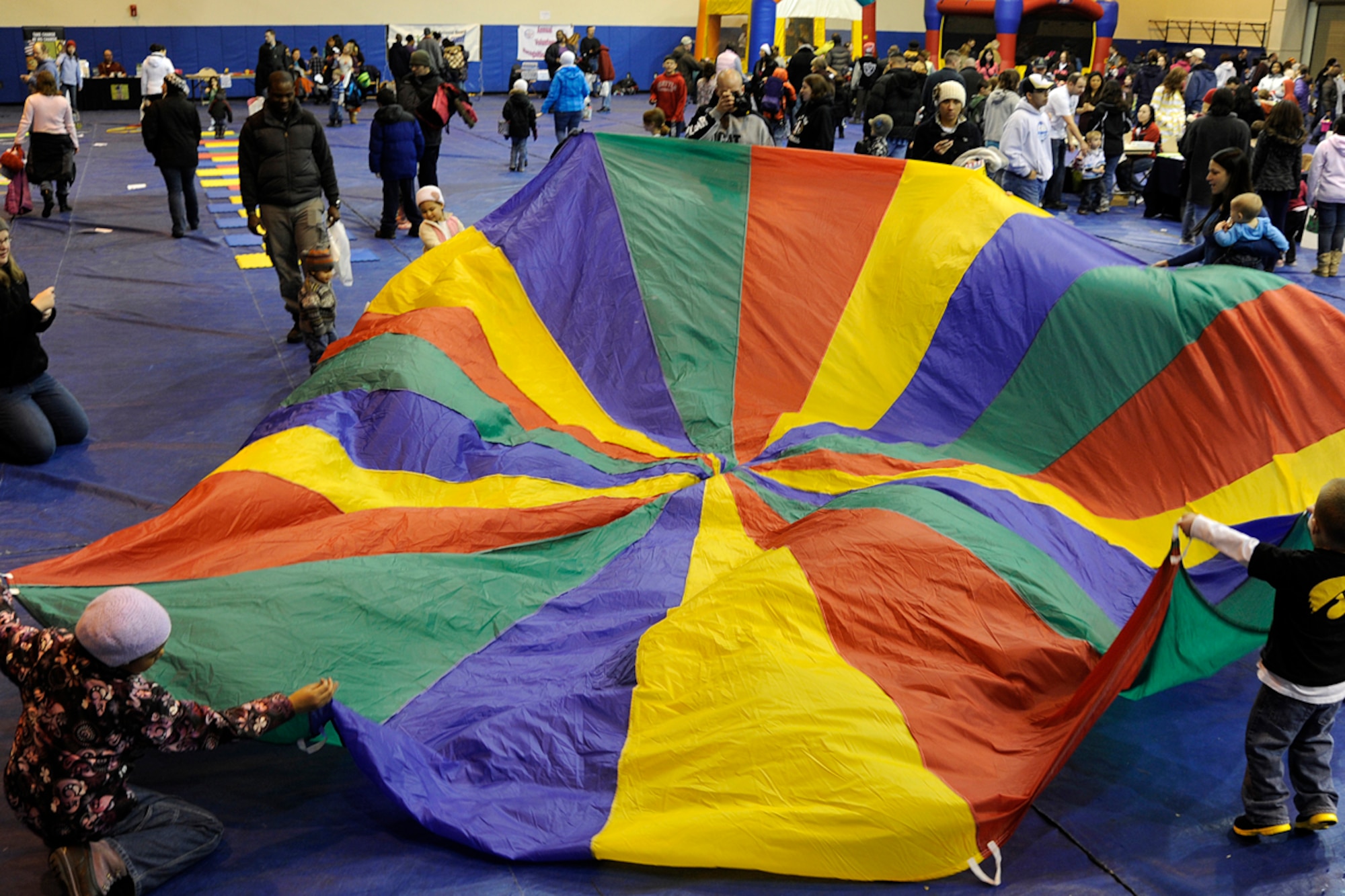 Children play with a parachute during the Family Fun and Fitness Fair inside the Buckner Gym on Joint Base Elmendorf-Richardson April 7, 2012. The fair was held as part of the Month of the Military Child in conjunction with the "Easter Eggstravaganza" that was held right outside the gym. (U.S. Air Force photo/Staff Sgt. Zachary Wolf)