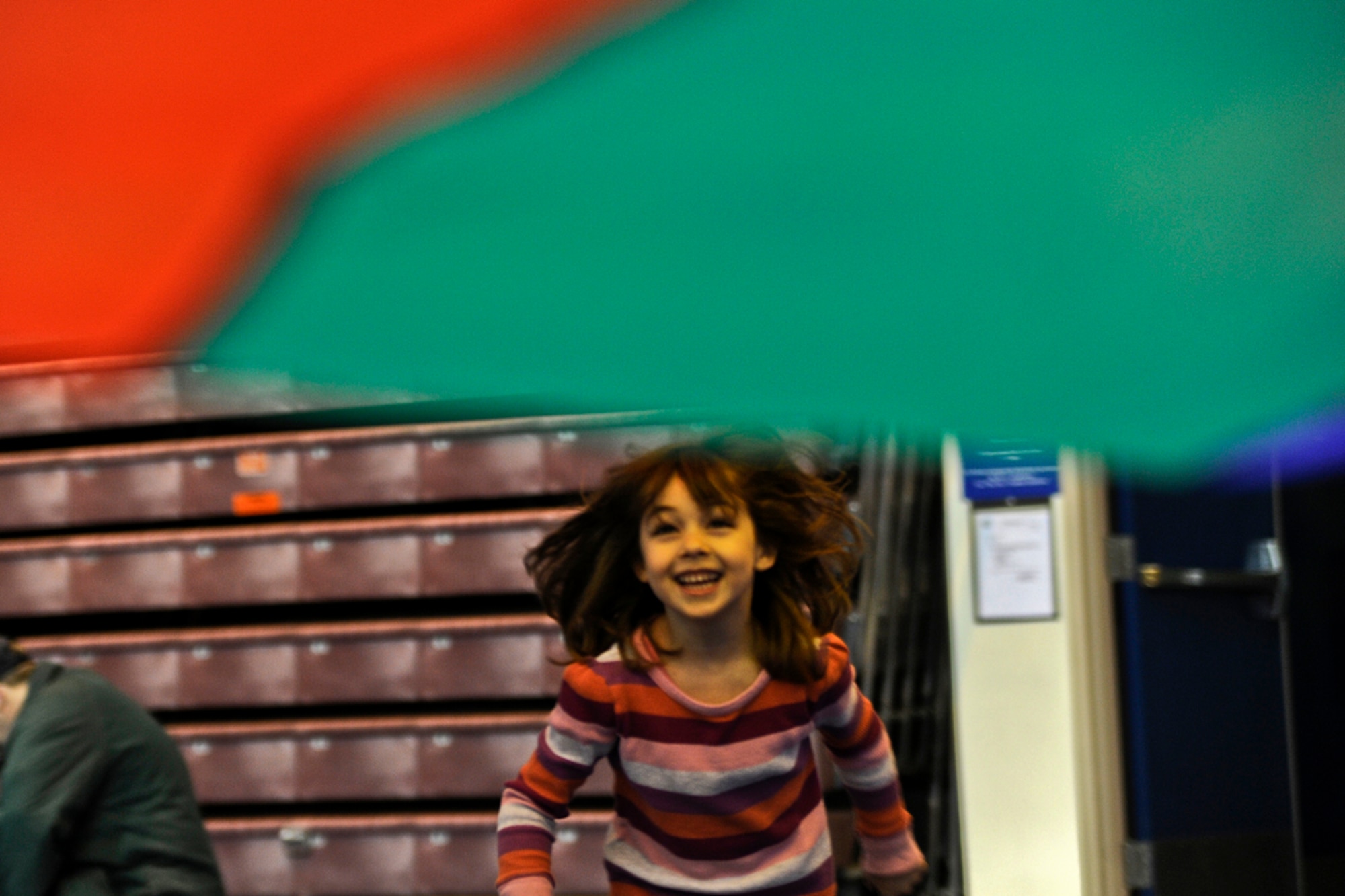 Simone Pelley, age 5, runs under a parachute during the Family Fun and Fitness Fair inside the Buckner Gym on Joint Base Elmendorf-Richardson April 7, 2012. The fair was held as part of the Month of the Military Child in conjunction with the "Easter Eggstravaganza" that was held right outside the gym. (U.S. Air Force photo/Staff Sgt. Zachary Wolf)