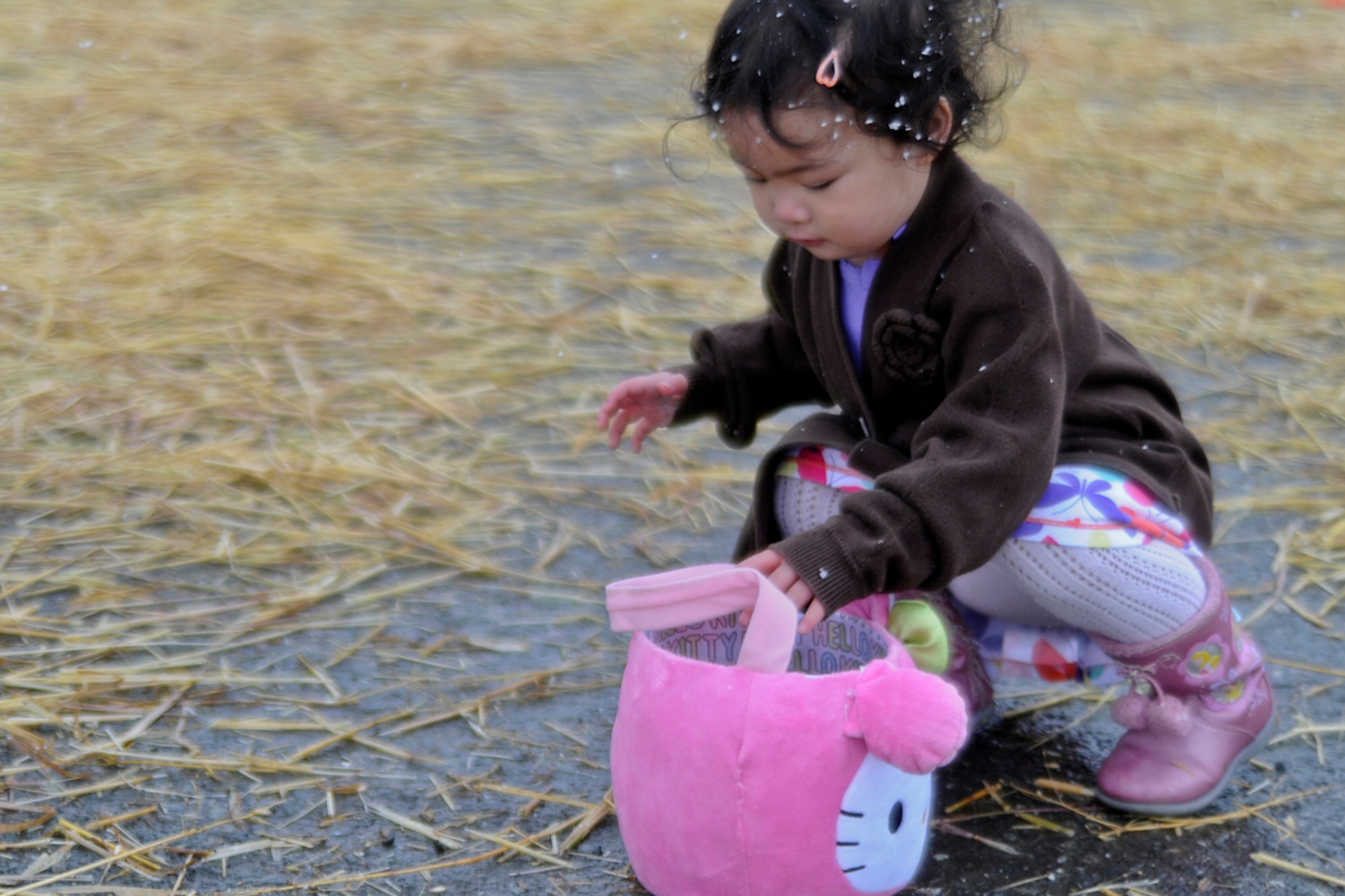 Ysabelle Nakasue, age 2, gathers eggs and puts them in her basket at the "Easter Eggstravaganza" on Joint Base Elmendorf-Richardson April 7, 2012. This was the first year that they combined the Air Force and Army Easter celebration and held it at Buckner gym. (U.S. Air Force photo/Staff Sgt. Zachary Wolf)