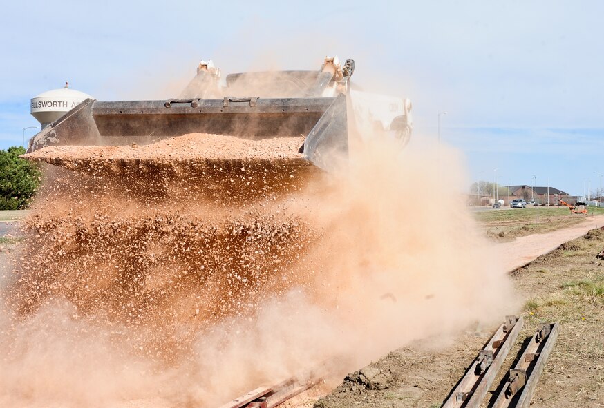 Kevin Holman, 28th Civil Engineer Squadron heavy equipment operator, drops a load of gravel on a pathway during a sidewalk construction project at Ellsworth Air Force Base, S.D., April 4, 2012. The gravel provides a strong foundation that increases the lifespan of the concrete being poured. (U.S. Air Force photo by Airman 1st Class Alystria Maurer/Released)
