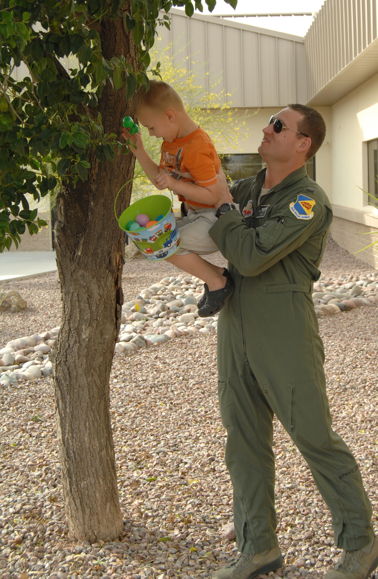 U.S. Air Force 1st Lt. Jared Graham, 355th Training Squadron A-10 pilot, holds up his son, William, as he picks an egg out of a tree at the 358th Fighter Squadron Easter egg hunt on Davis-Monthan Air Force Base, Ariz., April 6. (U.S. Air Force photo by Airman 1st Class Michael Washburn/Released) 