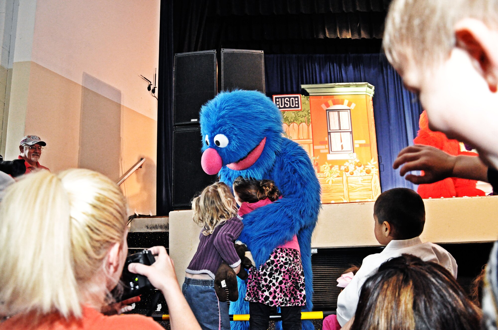 Grover hugs two audience members at the base theater at Scott Air Force Base, Ill., April 7, 2012.  Since its debut in July 2008, the Sesame Street/USO Experience for Military Families has taken its message to more than 248,000 troops and military families and performed 433 shows on 131 military bases in 33 states and eleven countries. (U.S. Air Force photo/Airman 1st Class Jake Eckhardt)