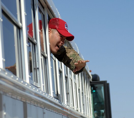 A member of the 820th RED HORSE Squadron waves to family members from a bus April 9, 2012 at Nellis Air Force Base, Nev. Members of the 820th RHS returned home from a deployment where they provided highly-mobile civil engineering capabilities in support of special operations worldwide. (U.S. Air Force photo by Senior Airman Jack Sanders)