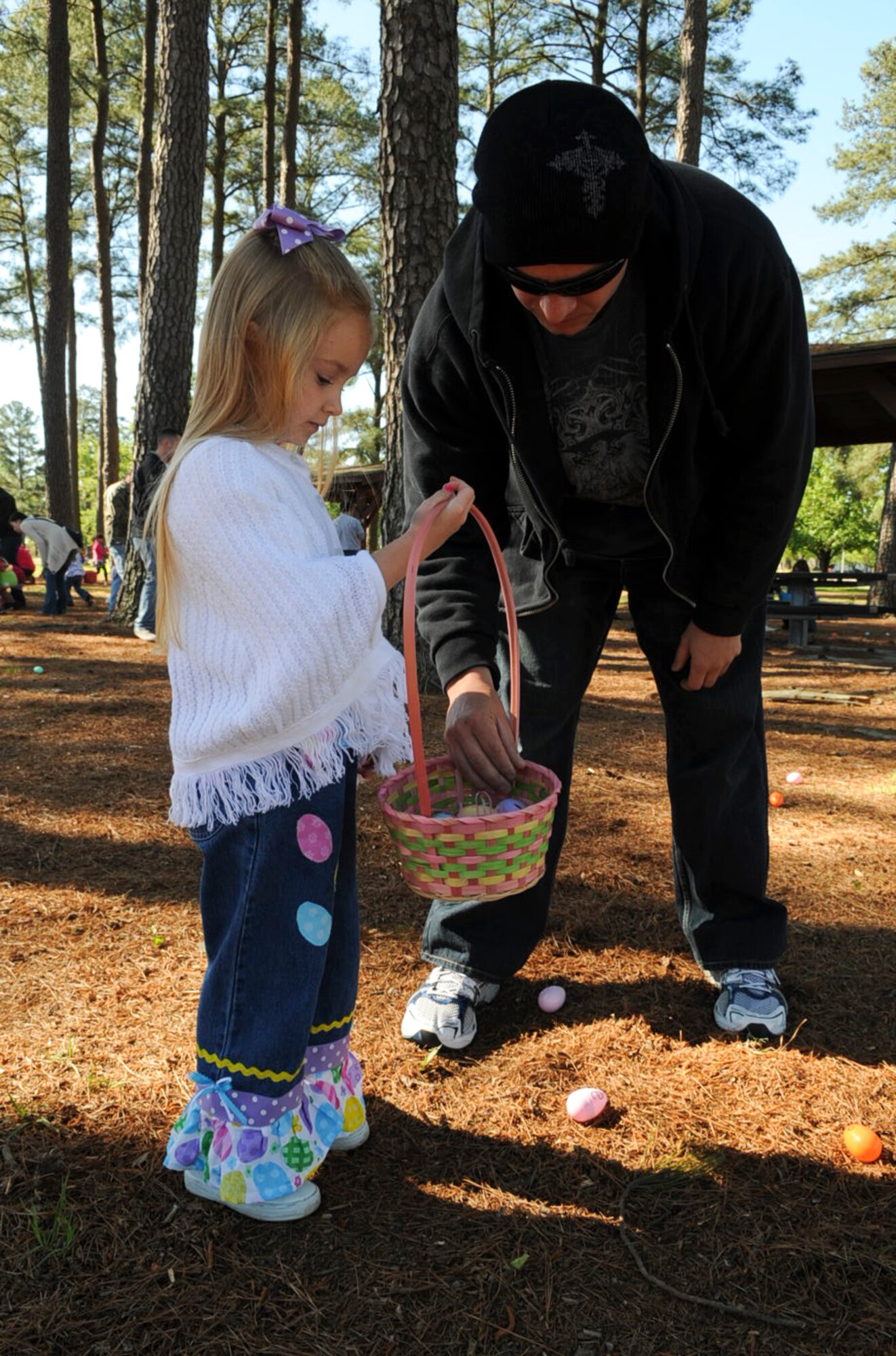 U.S. Air Force Tech. Sgt. Richard Carter and his daughter, Ebbee, 5, look at eggs in her basket during an Easter Egg Hunt at Debden Park on Seymour Johnson Air Force Base, N.C., April 7, 2012. The children collected eggs with letters that spelled “Easter” to redeem for treats. Carter is a crash recovery assistant program manager at the 4th Equipment Maintenance Squadron and hails from Concord, N.C. (U.S. Air Force photo/Airman 1st Class Aubrey Robinson/Released)