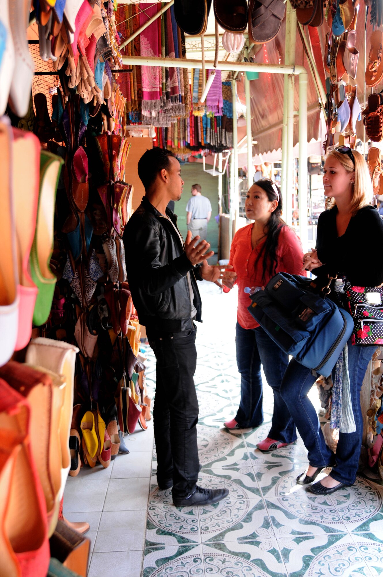 MOROCCO, Marakech -- Capt. Sylvia Kim, left, U.S. Air Forces Africa interpreter, interprets the French-speaking language for U.S. Army Sgt. Abigail Waldrop, AFAFRICA American Forces Network, as a French speaking vendor tells Waldrop and Kim about the shoes he is selling at the Jemaa el Fna Market here April 2. Kim and Waldrop visited the market with a group of service members as part of a culture exploration day before supporting the Marrakech Aeroexpo 2012. U.S. Air Forces Africa is participated in the third biennial Aeroexpo Marrekech to strengthen the partnerships with the nations involved and show commitment to security and stability in the region. This group of service members looked out for one another on their trip to the market ensuring no one was lost, left behind or injured. (U.S. Air Force photo by Senior Airman Natasha Stannard/Released)