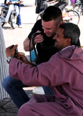MOROCCO, Marakech -- 1st Lt. Adam Gregory, left, U.S. Air Forces Africa public affairs officer, views a photo a snake charmer took of him at the Jemaa el Fna market here April 2. Gregory visited the market with a group of service members as part of a culture exploration day before supporting the Marrakech Aeroexpo 2012. U.S. Air Forces Africa participated in the third biennial Aeroexpo Marrekech to strengthen the partnerships with the nations involved and show commitment to security and stability in the region. This group of service members looked out for one another on their trip to the market ensuring no one was lost, left behind or injured. (U.S. Air Force photo by Senior Airman Natasha Stannard/Released)