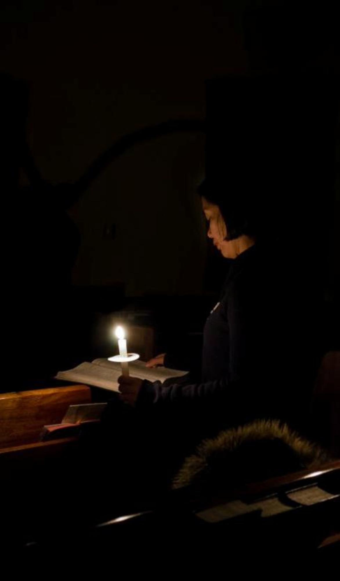 A parishioner attending the Catholic Easter Vigil Mass reads from her hymnal by candlelight on Holy Saturday at the base chapel, April 7, 2012, at Kunsan Air Base, Republic of Korea. The three other parts of the service are the Liturgy of the Word, Liturgy of Baptism and Liturgy of the Eucharist. (U.S. Air Force photo/Senior Airman Derrick Schwieters)