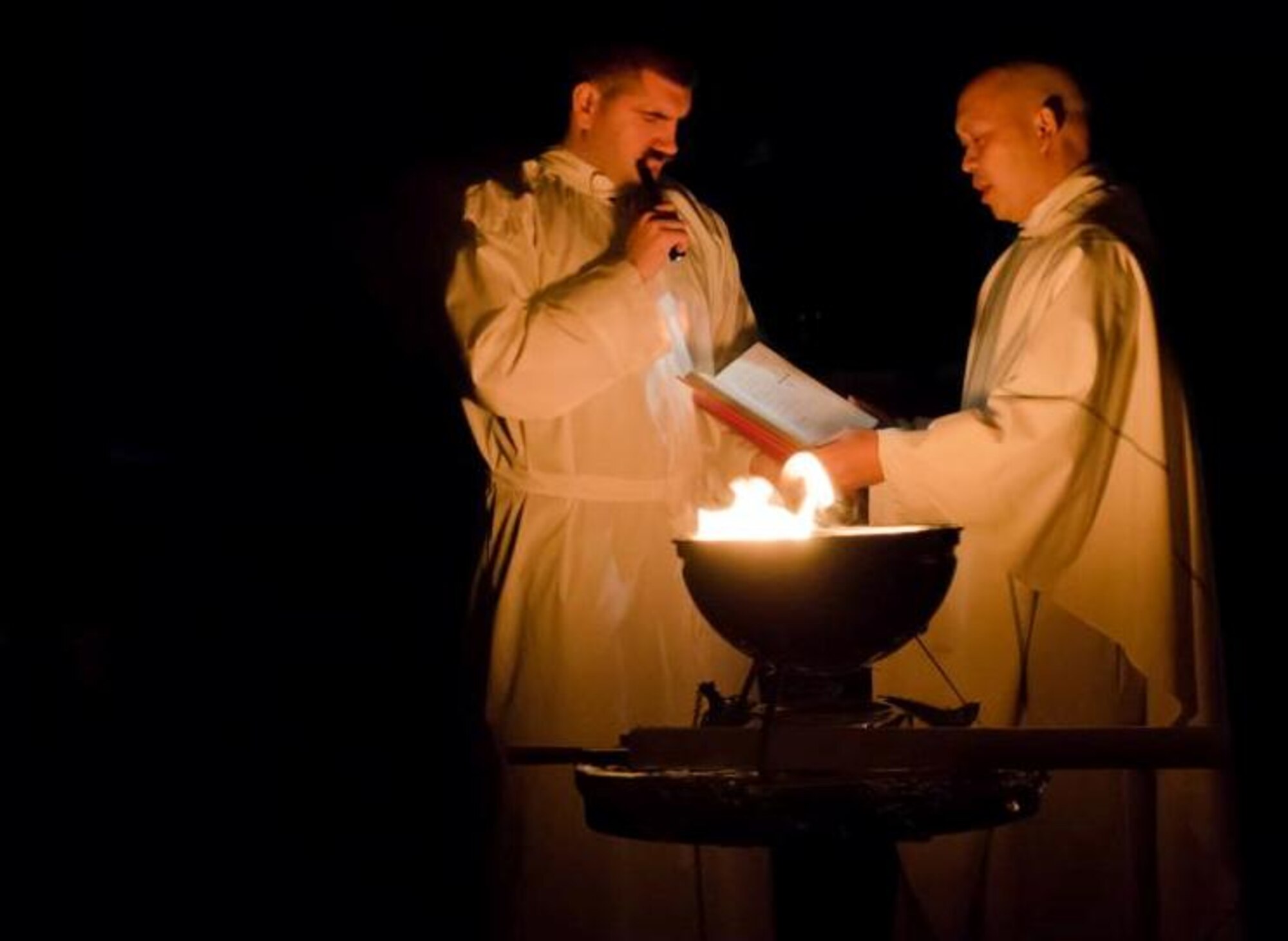 From the right, Chaplain (Capt.) Dennis DeGuzman, 8th Fighter Wing priest, blesses and lights a Paschal candle during the Catholic Easter Vigil Mass at the base chapel April 7, 2012, on Kunsan Air Base, Republic of Korea. The Paschal candle will be used throughout the season of Easter for special events at the chapel as customary with religious traditions. (U.S. Air Force photo/Senior Airman Derrick Schwieters)