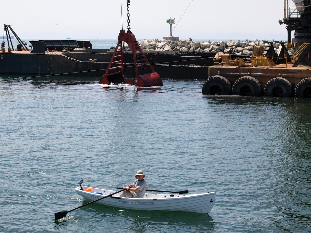 A Whitehall Spirit Rowing Club member rows past the dredge Paula Lee April 8 at Marina del Rey Harbor. The dredge is removing sediment from the navigation channel to enhance safety for government, commercial and recreational boaters.
