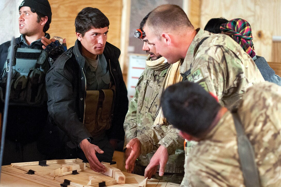 Afghan police officers and U.S. Army paratroopers use a model terrain board of a village to practice for a raid to find a suspected weapons cache in a compound in southern Ghazni province, Afghanistan, April 7, 2012. The paratroopers are assigned to the 82nd Airborne Division’s 1st Brigade Combat Team. The Afghan police will take point on the operation.