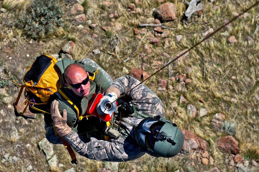 Army Sgt. Nathan McLaughlin, right, rescues Army Staff Sgt. Christian Larsen, posing as a lost hiker, as they are hoisted into a UH-60 Black Hawk helicopter during a search and rescue training exercise on Camp W.G. Williams in Riverton, Utah, April 3, 2012. McLaughlin, a standardization instructor, and Larsen, a medic, are assigned to Company C, 1st General Support Aviation Battalion, 171st Aviation Regiment, Utah Army National Guard.