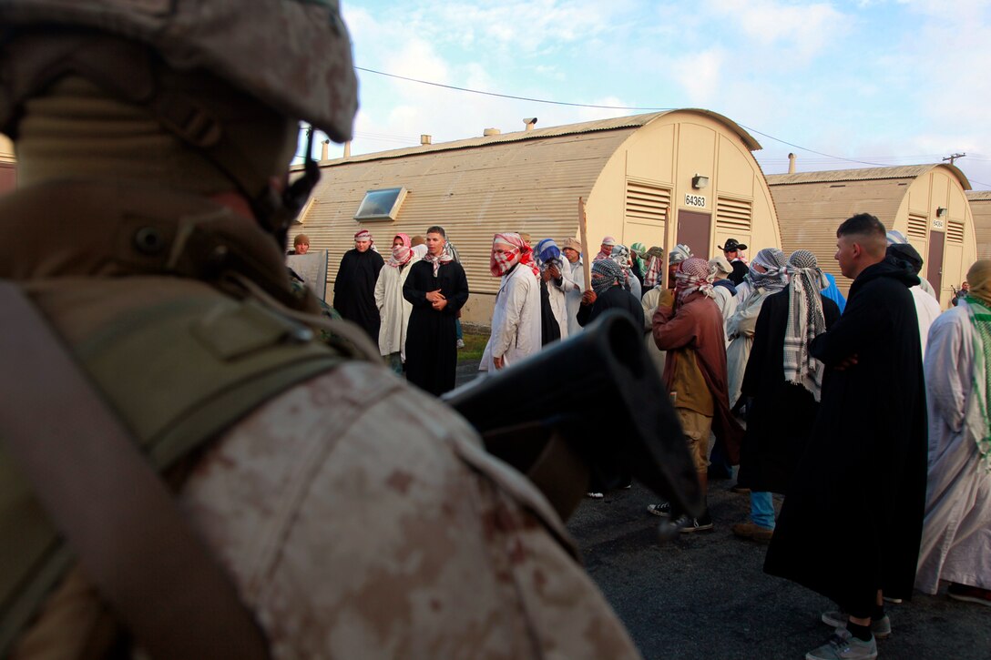 A Marine with the Military Police Detachment, Combat Logistics Battalion 15, 15th Marine Expeditionary Unit, posts security during non-combatant evacuation operation training as role players turn a peaceful protest into a riot, here, April 11. The NEO was the final training evolution during MEU Exercise, held April 2-12, to train the major subordinate elements of the 15th MEU to operate as a Marine Air Ground Task Force.