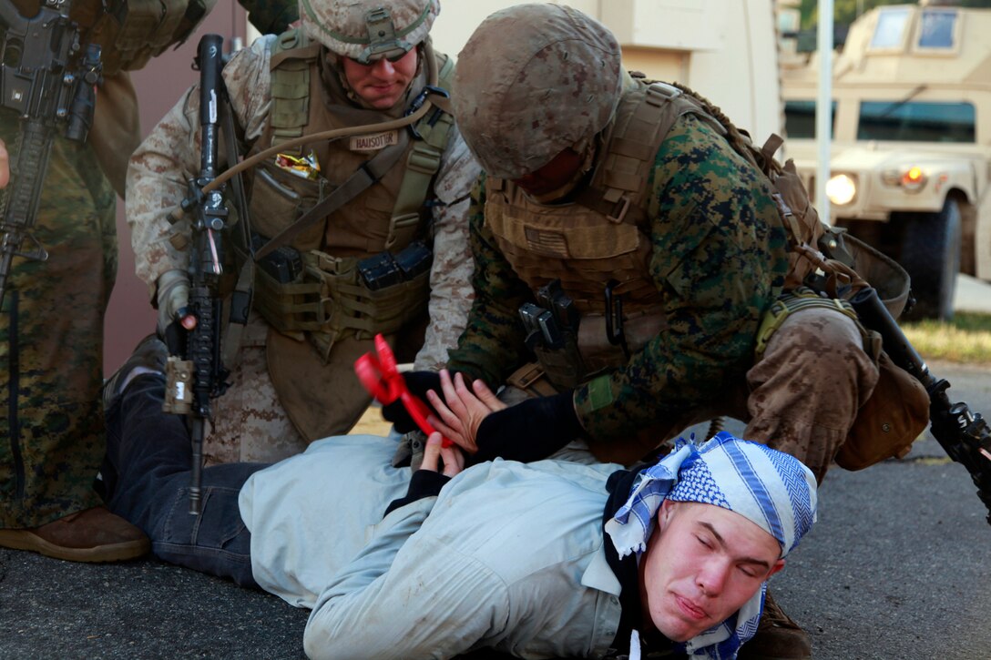 Marines with the Military Police Detachment, Combat Logistics Battalion 15, 15th Marine Expeditionary Unit, place Lance Cpl. Riley J. Leblanc, who is acting as a role player, into their custody during a non-combatant evacuation operation training, here, April 11. The NEO was the final training evolution during MEU Exercise, held April 2-12, to train the major subordinate elements of the 15th MEU to operate as a Marine Air Ground Task Force. Leblanc, 21, is a native of Tacoma, Wash., and serves as a flight-line mechanic with Marine Medium Helicopter Squadron 364, 15th MEU.