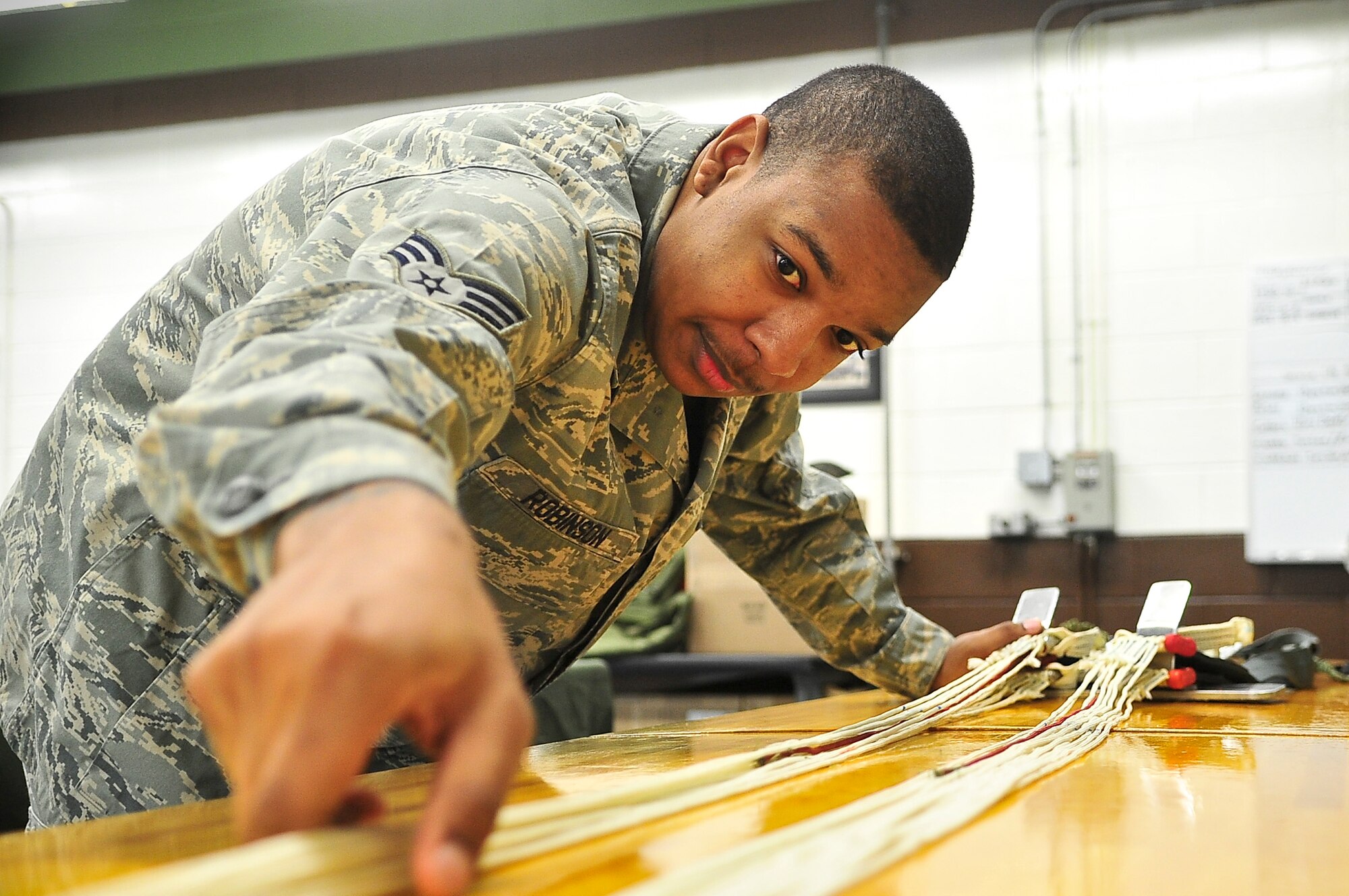 Senior Airman Dominique Robinson, 51st Operations Support Squadron aircrew flight equipment journeyman, aligns the suspension line of a de-acceleration canopy April 10, 2012. The canopy is used as a second line of protection to slow down aircraft. (U.S. Air Force photo/Senior Airman Adam Grant)