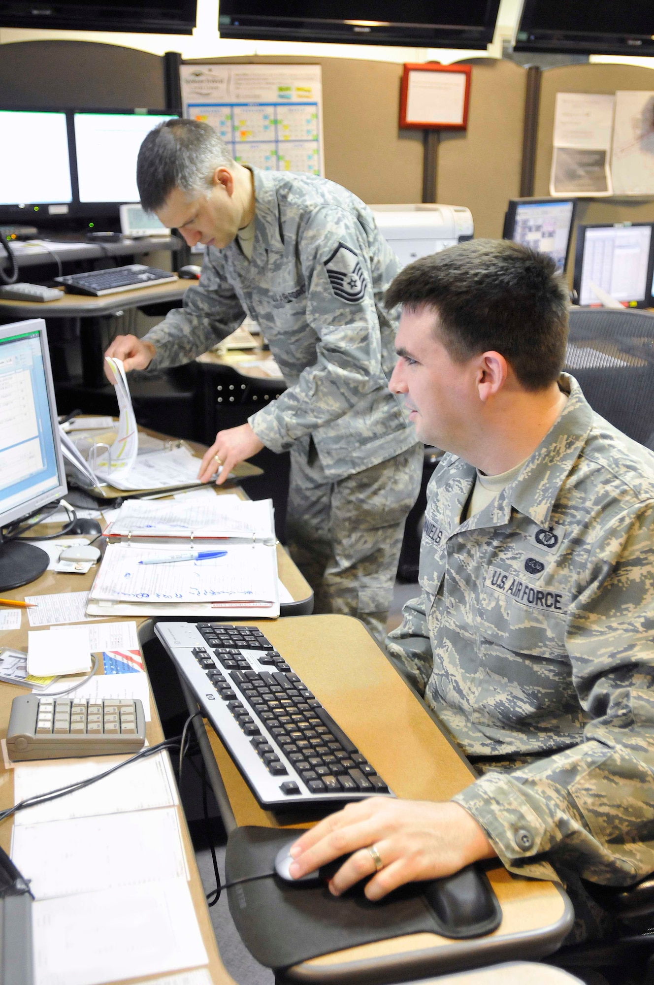 Master Sgt. William Mader and Tech. Sgt. Jon Daniels, 141st Air Refueling Wing Command Post controllers, verify checklist procedures during a training exercise at Fairchild Air Force Base, Wash., recently. (U.S. Air Force photo by Staff Sgt. Johanna Brooks/Released)
