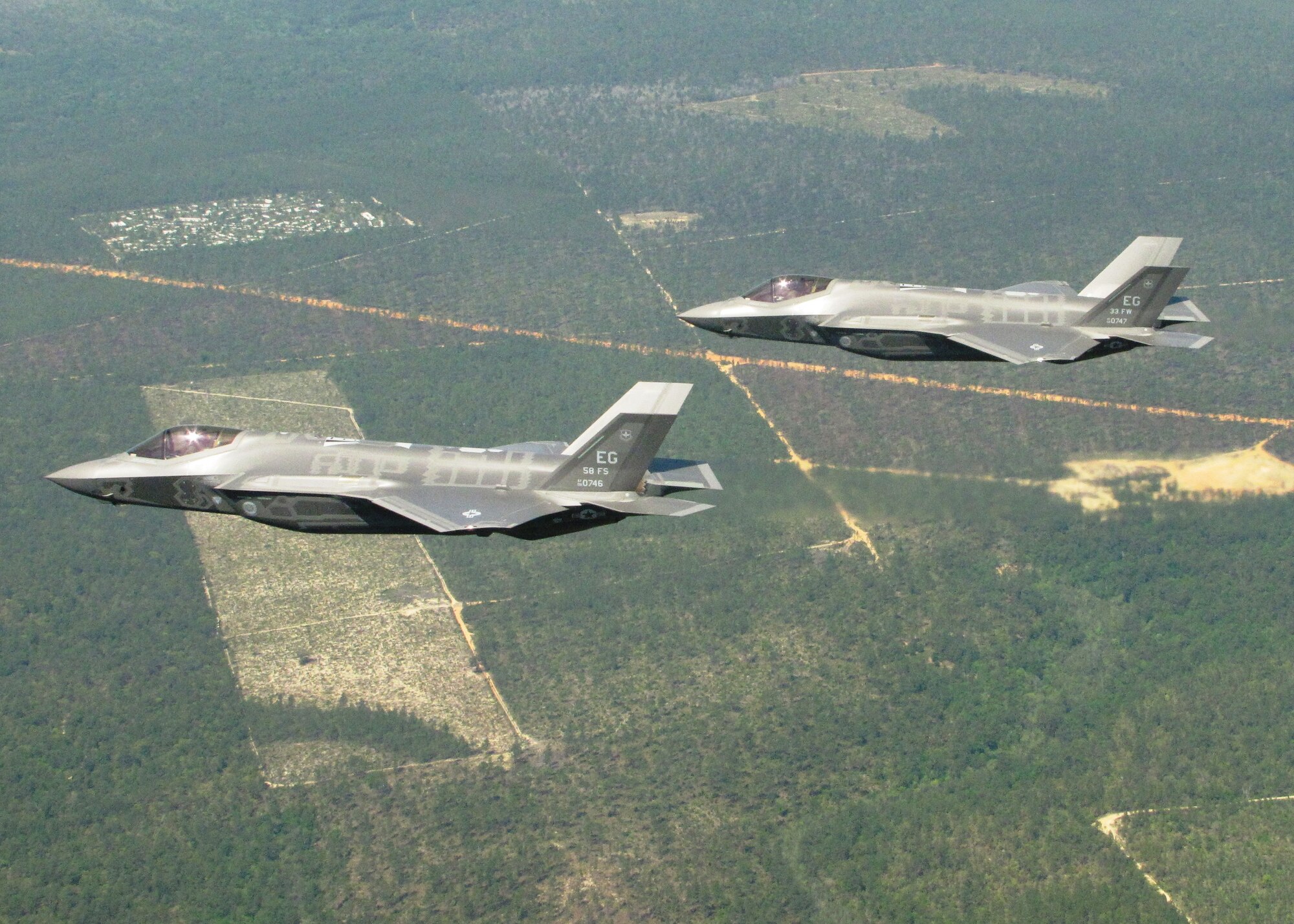 Two F-35A Lightning IIs from the 33rd Fighter Wing soar over Eglin Air Force Base's range during the unit’s first joint strike fighter formation flight April 10. Lt. Col. Eric Smith, 58th Fighter Squadron director of operations, flew the lead aircraft while Marine Maj Joseph Bachmann, Fighter Attack Training Squadron 501 aircraft maintenance officer, flew wingman. The pilots, both first in their service qualified to fly the 5th generation aircraft, were validating pilot syllabus objectives in preparation for future training. The 33rd FW is responsible for F-35 A/B/C pilot and maintainer training for the Marine Corps, Navy, Air Force, and in the future, at least eight coalition partners. (U.S. Air Force photo/Capt. Ryan Seymour)