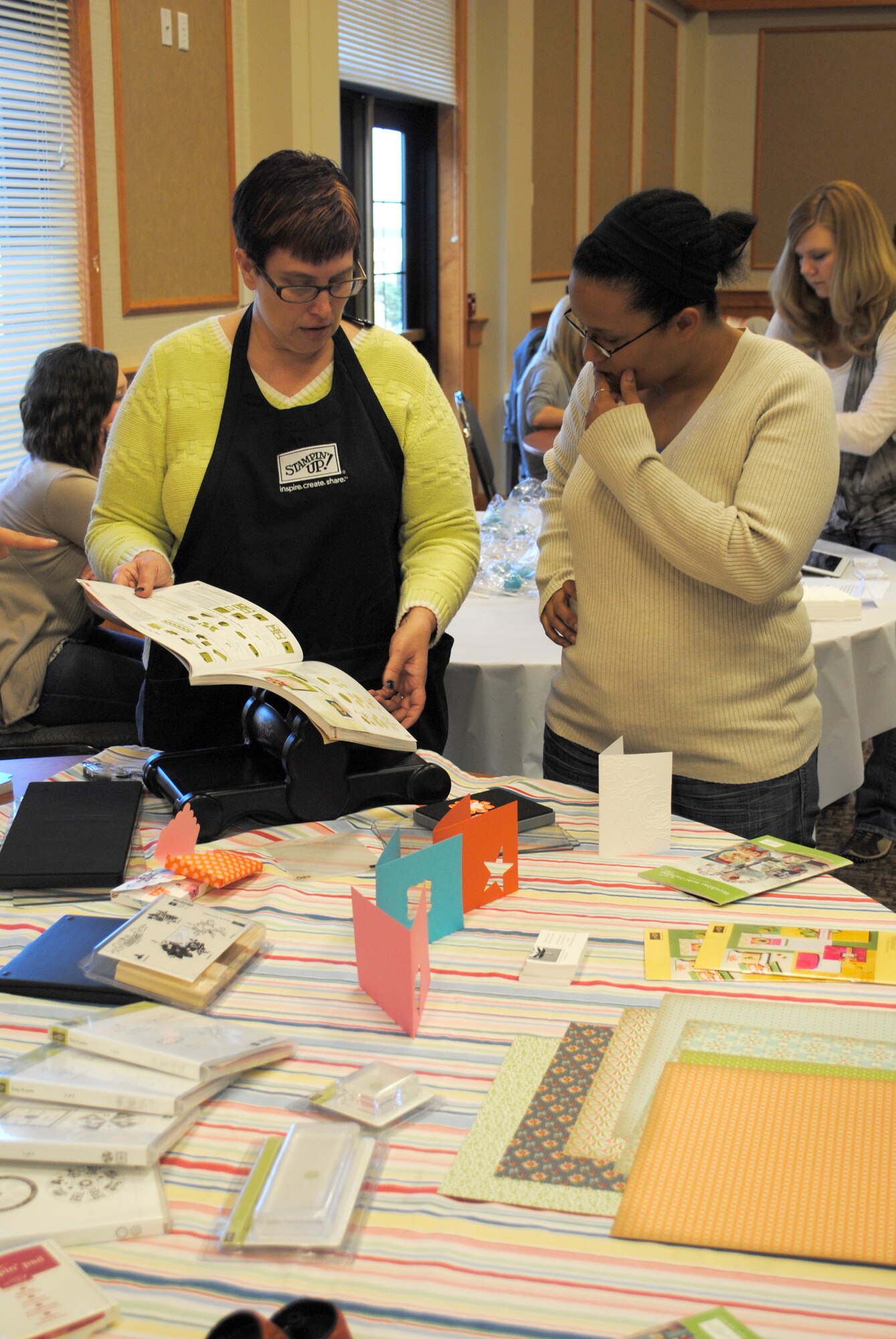 Beth Fasting, 341st Missile Wing Protestant recoordinator, shows Staff Sgt. Shaleena Pulliam, 341st Medical Operations Squadron dental assistant, a book full of scrapbooking ideas. Fasting was displaying and selling scrapbook supplies among other members of Team Malmstrom at the base's Flea Market. (U.S. Air Force photo/Airman 1st Class Cortney Paxton)