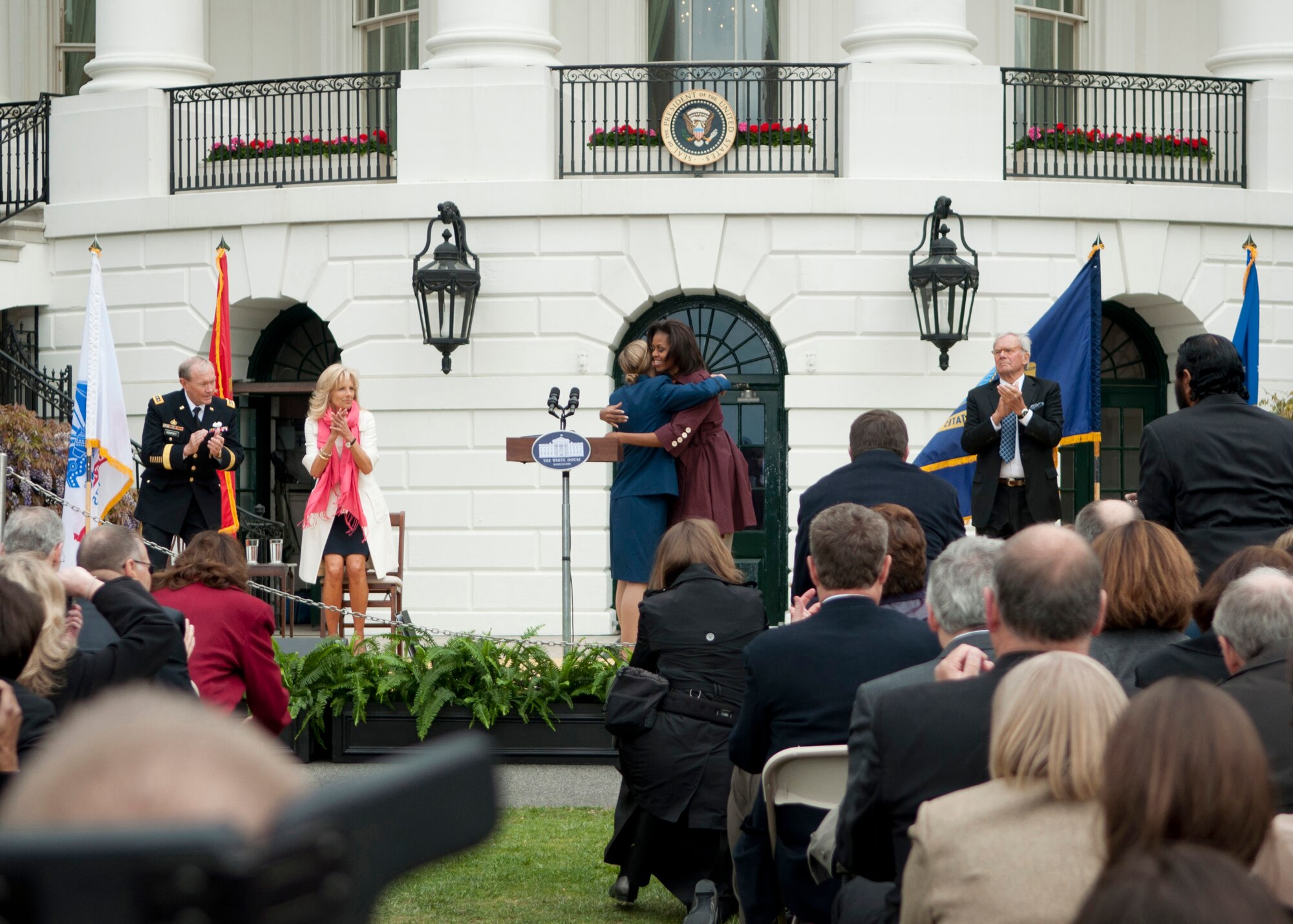 Cadet Staff Sgt. Moranda Hern, Air Force Academy sophomore, receives a hug from First Lady Michelle Obama after Hern spoke at the first anniversary of Joining Forces ceremony on the south lawn of the White House April 11, 2012. Also on stage were Chairman of the Joint Chiefs of Staff U.S. Army Gen. Martin E. Dempsey; Jill Biden, the vice-president’s wife; and Tom Brokaw, television journalist.   Hern was one of the 20 finalists in the Joining Forces Community Challenge that recognized citizens, communities and organizations for their efforts in supporting military families. Hern was one of the 20 finalists in the Joining Forces Community Challenge for starting the Sisterhood of the Traveling BDUs organization that aims to help daughters ages 13-18 of military members connect and build relationships.  The challenge was part of the Joining Forces program, pioneered by First Lady Michelle Obama and Jill Biden, which is a national initiative that mobilizes all sectors of society to support military members and their families. (Air Force photo by Tech. Sgt. Jess D. Harvey)