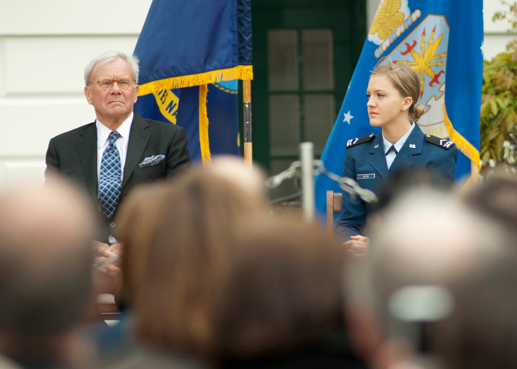 Tom Brokaw, television journalist, and Cadet Staff Sgt. Moranda Hern, Air Force Academy sophomore, listen to the First Lady’s speech at the First Anniversary of Joining Forces ceremony on the south lawn of the White House April 11, 2012.  Joining Forces, pioneered by First Lady Michelle Obama and Jill Biden, is a national initiative that mobilizes all sectors of society to support military members and families. Hern was one of the 20 finalists in the Joining Forces Community Challenge for starting the Sisterhood of the Traveling BDUs organization that aims to help daughters ages 13-18 of military members connect and build relationships. (Air Force photo by Tech. Sgt. Jess D. Harvey)