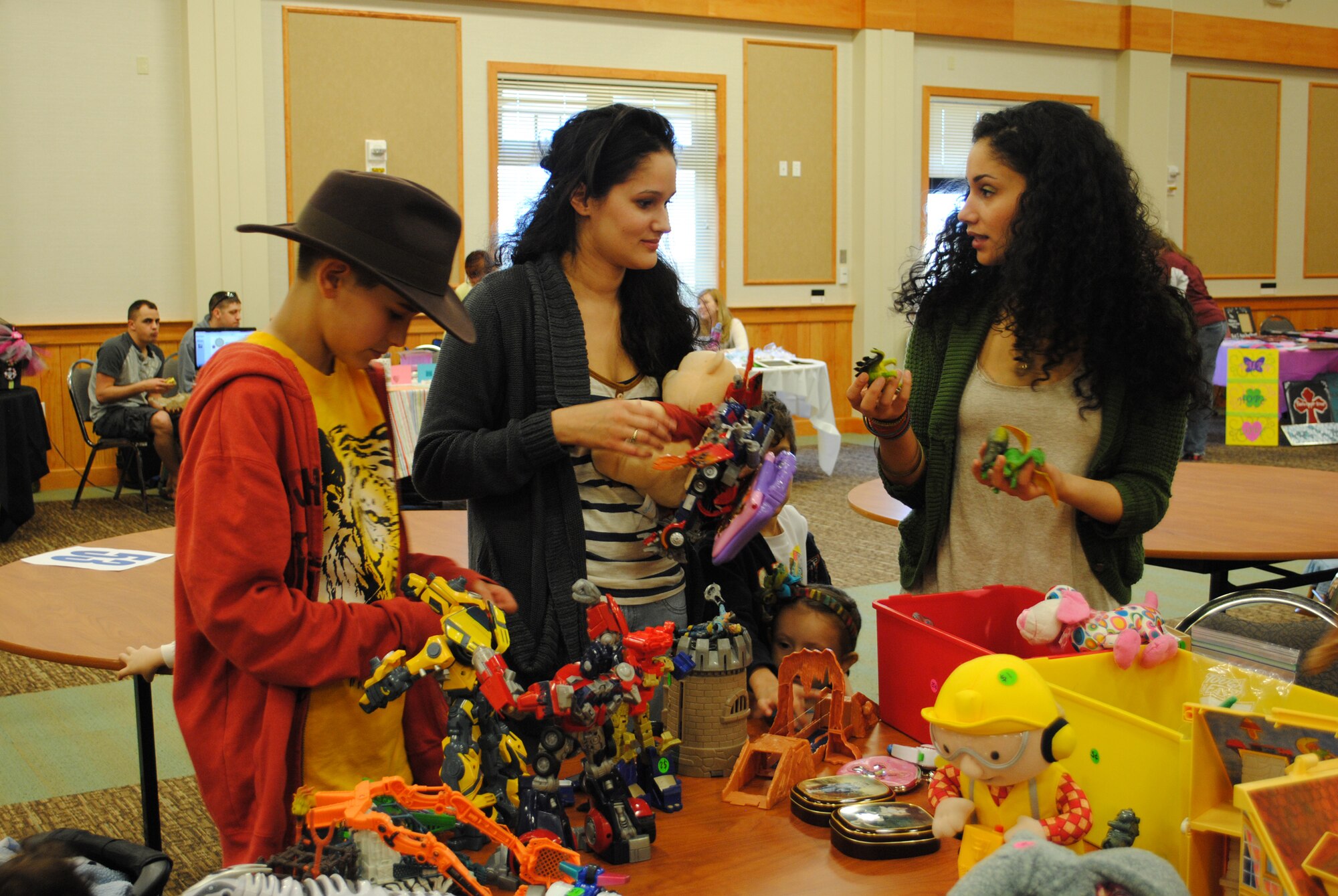 Senior Airman Sulai Baddour, 341st Force Support Squadron evaluations technician, right, and her sister Debbie Maldonado look through some of Eli Laborde-Martin's old toys as he watches. Toys were among many things, including jewelery, clothes, bags, woodwork, food and much more, being sold at the Flea Market held at the Grizzly Bed March 31. (U.S. Air Force photo/Airman 1st Class Cortney Paxton)