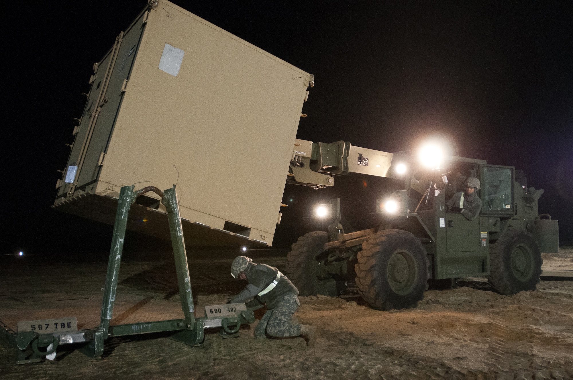 U.S. Army Specialist Amanda Alaeluci positions a cargo container using a 10,000-pound all-terrain forklift as Private 1st Class Callie Rankin prepares a truck platform to receive the container March 26, 2012, during Exercise Eagle Flag at Joint Base McGuire-Dix-Lakehurst, N.J. Both Soldiers are assigned to the 690th Rapid Port Opening Element, based at Fort Eustis, Va. The element is working with the Kentucky Air National Guard's 123rd Contingency Response Group to establish an aerial port at Lakehurst Naval Air Engineering Station within 24 hours of arrival. (U.S. Air Force photo by Maj. Dale Greer)