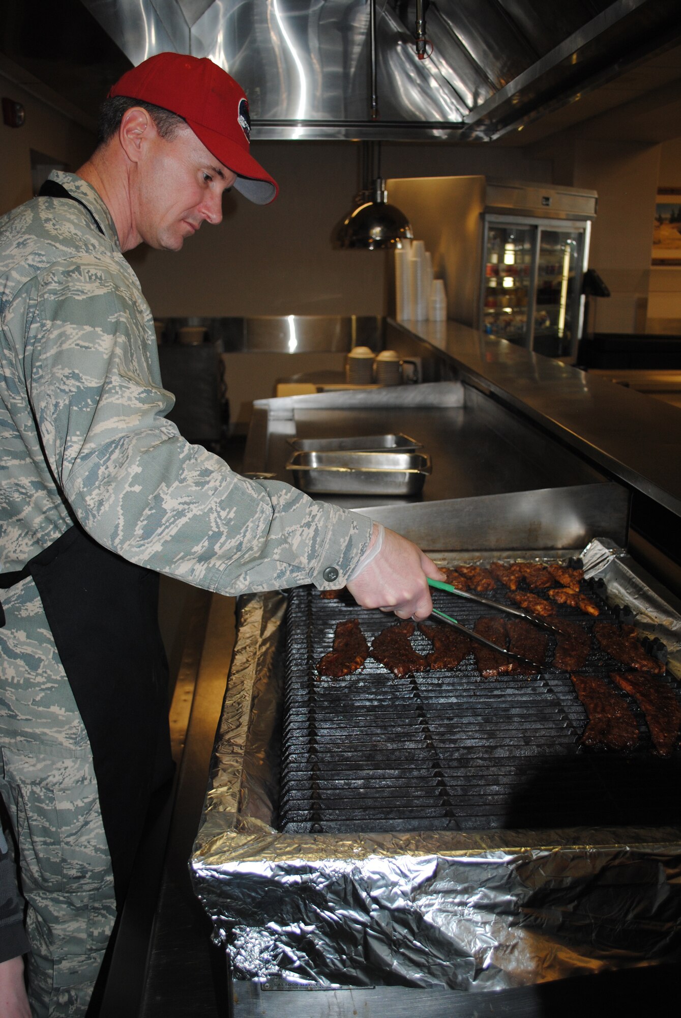 Col. Mark Zimmerhanzel, 819th RED HORSE Squadron commander, turns some meat over on the grill for his team's signature dish, Chicken Pad Thai. (U.S. Air Force photo/Senior Airman Kristina Overton)