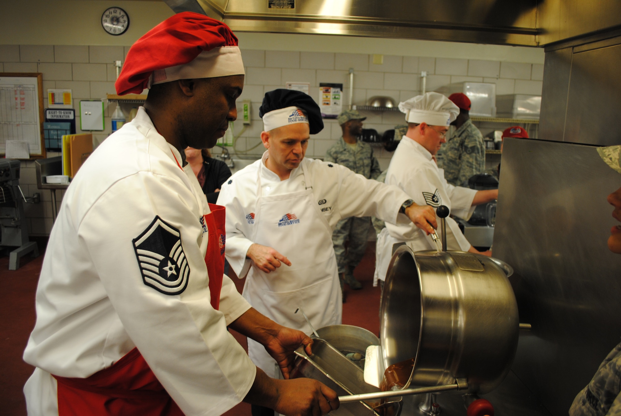 Blake finishes the sauce for his team's Spicy Sichuan Chicken for the Warrior Chef Competition March 28 at the Elkhorn Dining Facility. His partner in the competition, Lt. Col. Craig Ramsey, squadron commander, works diligently on another recipe. (U.S. Air Force photo/Senior Airman Kristina Overton)