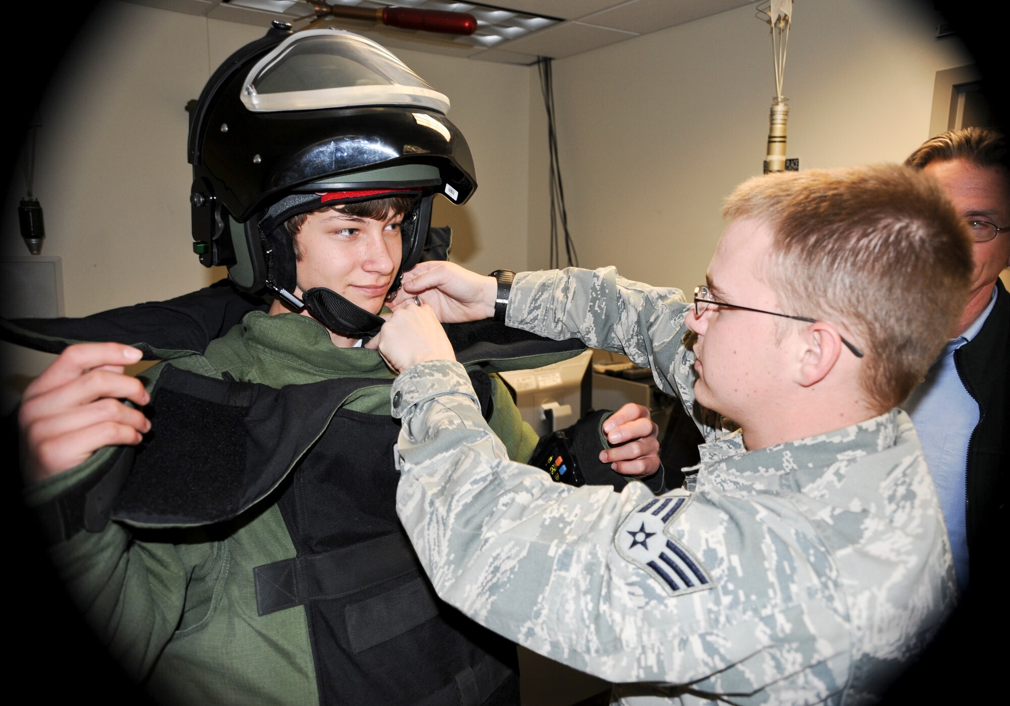 Senior Airman Chris Jones, 92nd Civil Engineer Squadron explosive ordinance disposal technician, assists a boy from the Morning Star Boys Ranch as he dons the EOD bomb suit at Fairchild Air Force Base, Wash., April 6, 2012. The group of boys toured the base as part of a community relations initiative developed to strengthen the relationship between the base and its surrounding communities. (U.S. Air Force photo by Senior Airman Benjamin Stratton/Released)