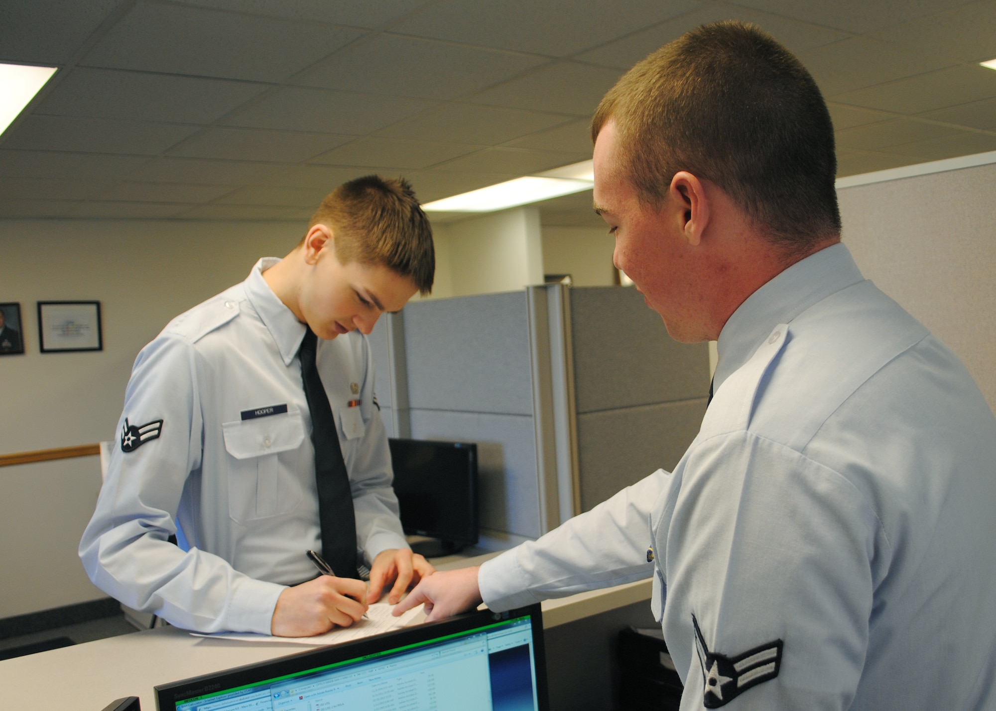 Airman 1st Class Richie Peart, right, 341st Comptroller Squadron customer service technician, helps Airman 1st Class Nathaneal Hooper, 341st Force Supports Squadron customer service, fill out an Air Force form. (U.S. Air Force photo/Airman 1st Class Cortney Paxton)