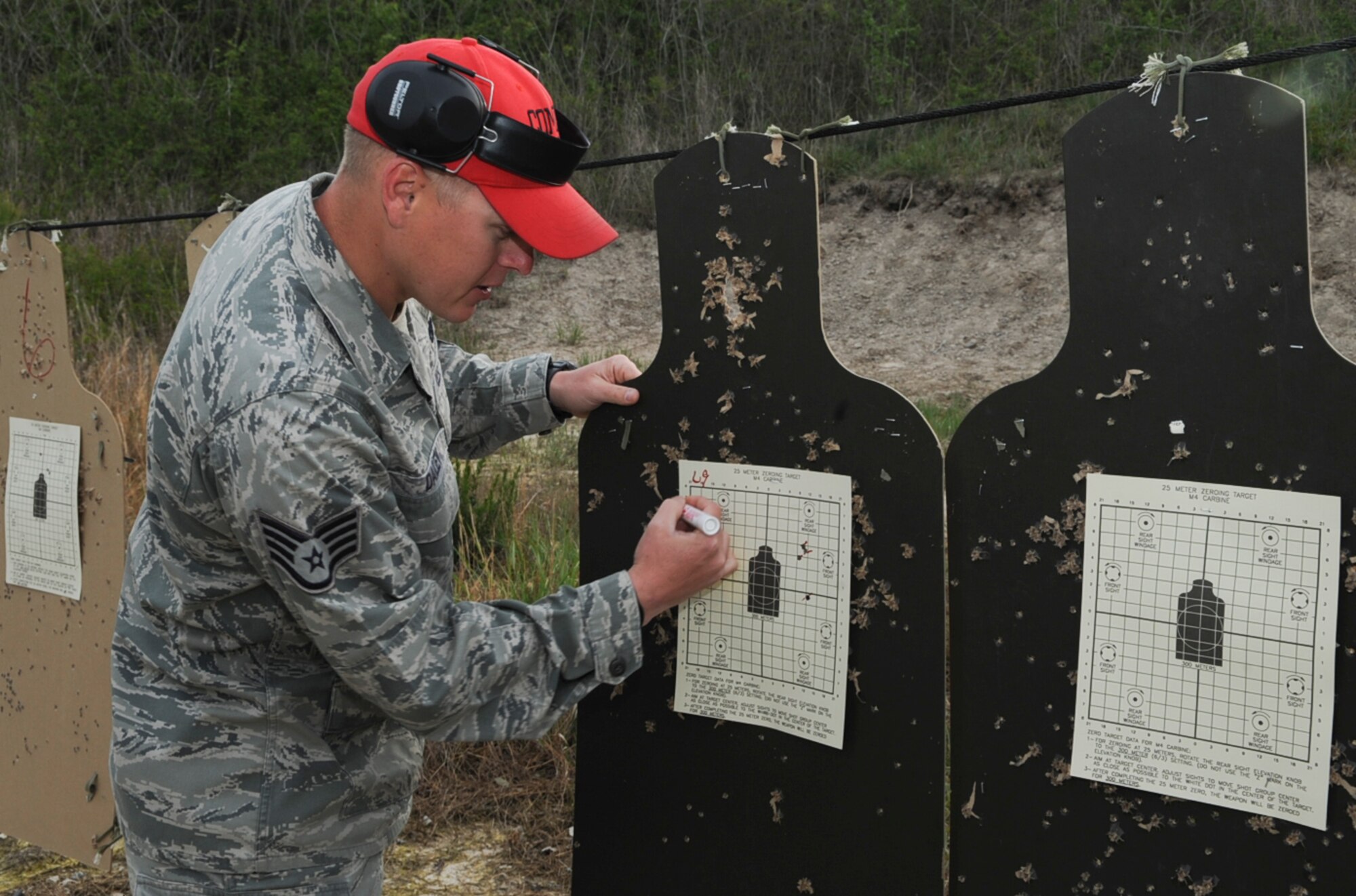 U.S. Air Force Staff Sgt. Tommy Dailey marks bullet holes on a target at Howell Woods Firing Range in Smithfield, N.C., April 10, 2012. Combat arms instructors mark where rounds impact a target in order to gauge necessary weapon adjustments to assist the qualifier in shooting more accurately. Dailey, 4th Security Forces Squadron assistant noncomissioned officer in charge of combat arms, hails from DeSoto, Ill. (U.S. Air Force photo/Airman 1st Class Aubrey Robinson/Released)