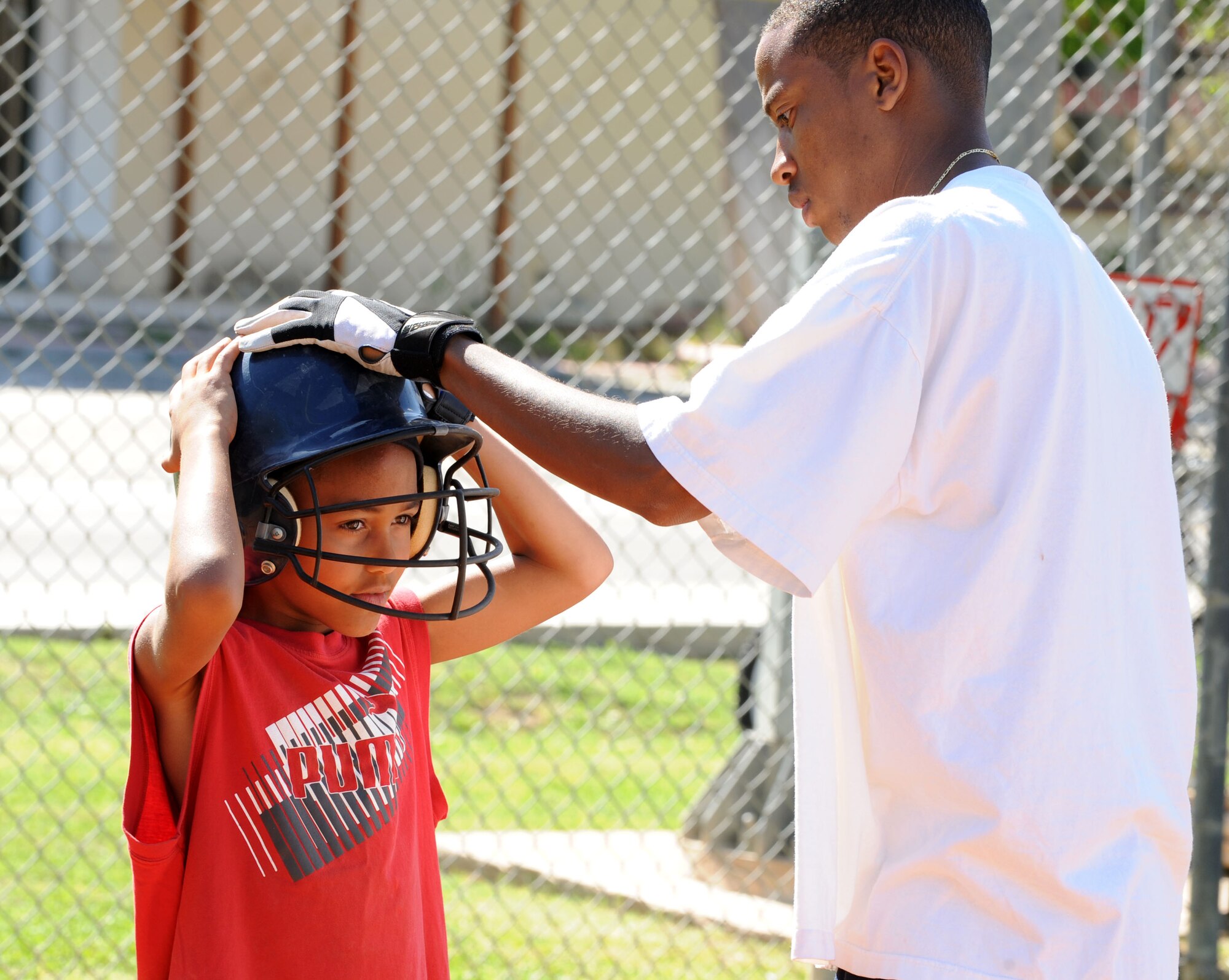 Marcus Prentiss, 39th Communications Squadron, secures his son's helmet during baseball spring training camp April 10, 2012, at Incirlik Air Base, Turkey. Players ages 9-18 took part in the training to prepare for the Youth Center Baseball Tournament, which kicks off April 21. (U.S. Air Force photo by Senior Airman Jarvie Z. Wallace/Released)