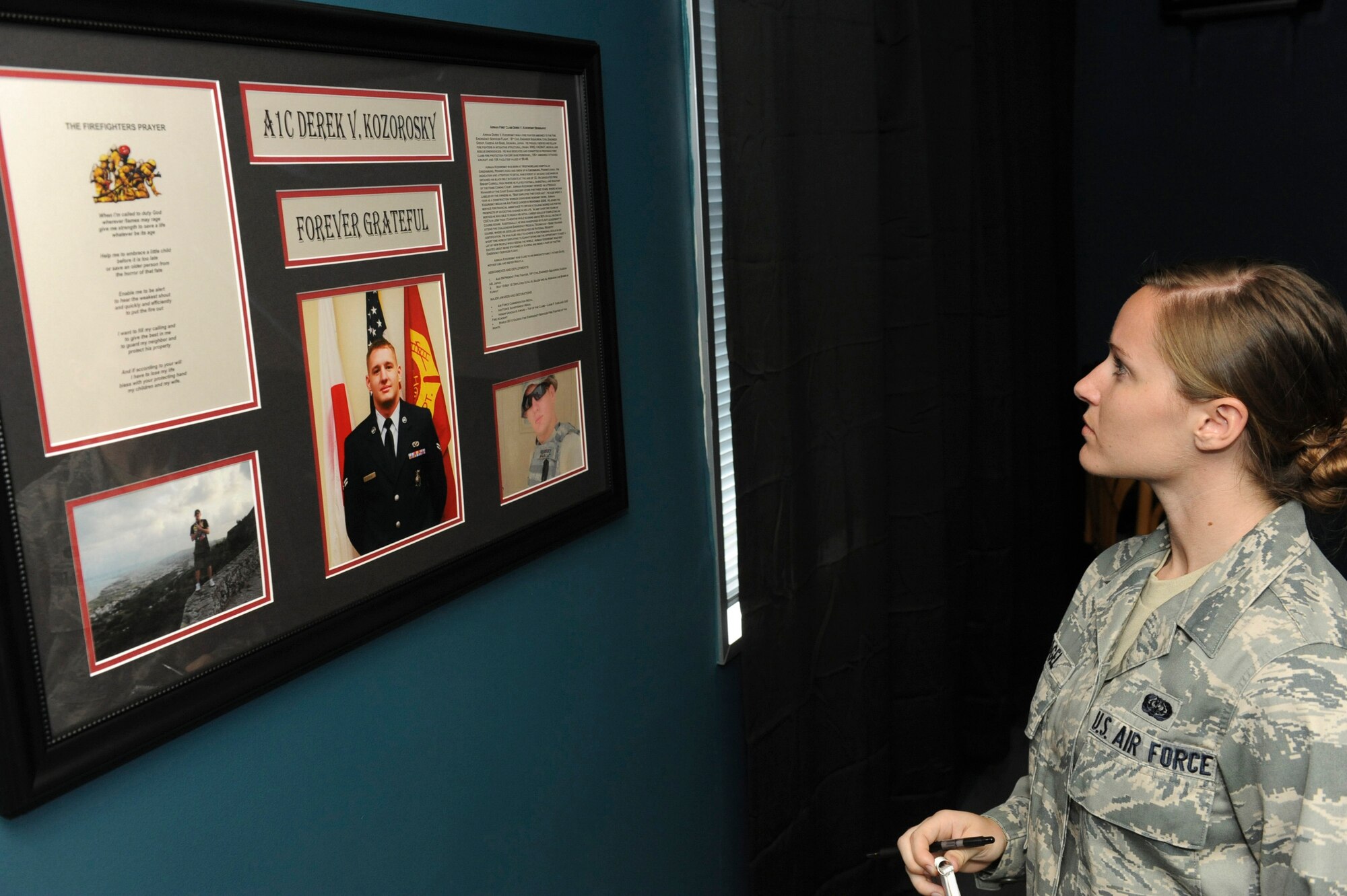 U.S. Air Force Airman 1st Class Tiffany Fogel, 82nd Reconnaissance Squadron knowledge operator, looks at a picture of Airman 1st Class Derek Kozorosky during the grand opening of the "Koz Mahal" on Kadena Air Base, Japan, April 11, 2012. "Koz Mahal" was dedicated in honor of Kozorosky, a Kadena firefighter who passed away following a vehicle mishap last year. (U.S. Air Force photo by Airman 1st Class Justin Veazie/released)