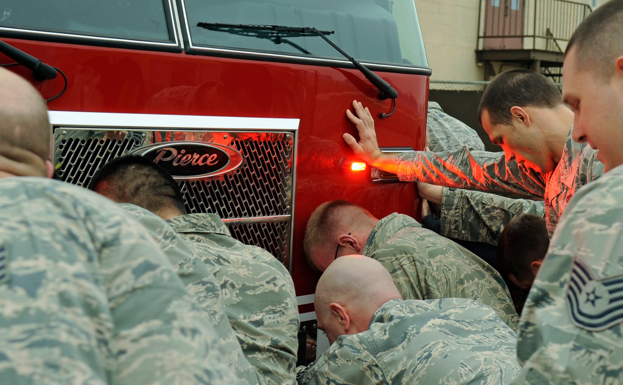 Airmen from the 8th Civil Engineer Squadron along with other Wolf Pack members help push a new fire truck into the station on Kunsan Air Base, Republic of Korea, April 9, 2012, as part of a 200-year-old tradition among firefighters. Today, firefighters continue this tradition when receiving a new fire truck as a way for community members to help honor the fire station and the brave men and women who serve there. (U.S. Air Force photo/Senior Airman Jessica Hines) 